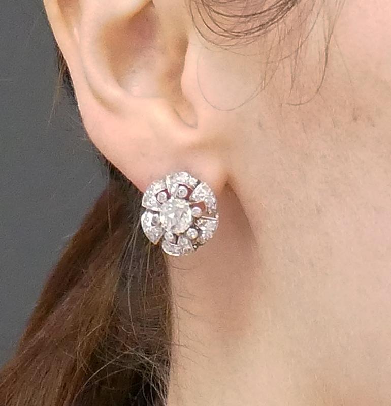 A beautiful pair of vintage platinum diamond earrings from the roaring 1930s. 
While designed as classic cluster earrings, this Art Deco inspired platinum diamond pair features unique details. Resembling a flower, each earring features in the center