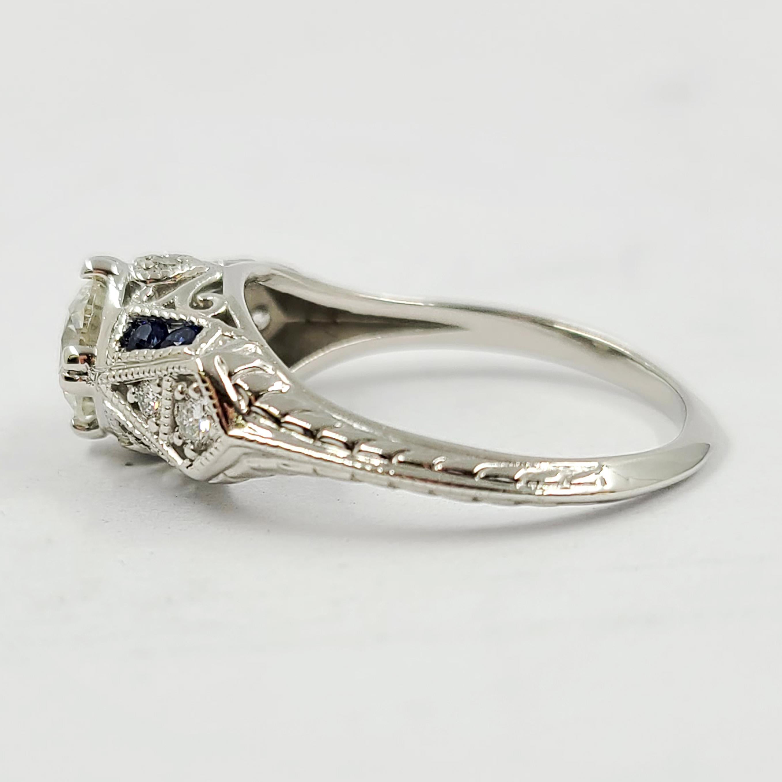 Platinum Diamond Ring Featuring A 0.90 Carat Round Diamond of G Color & SI Clarity Accented By 8 Sapphires Totaling 0.16 Carats & 6 Round Diamonds Totaling 0.10 Carats. Engraved Detail & Cutout Gallery. Current Finger Size Is 6.75; Purchase Includes