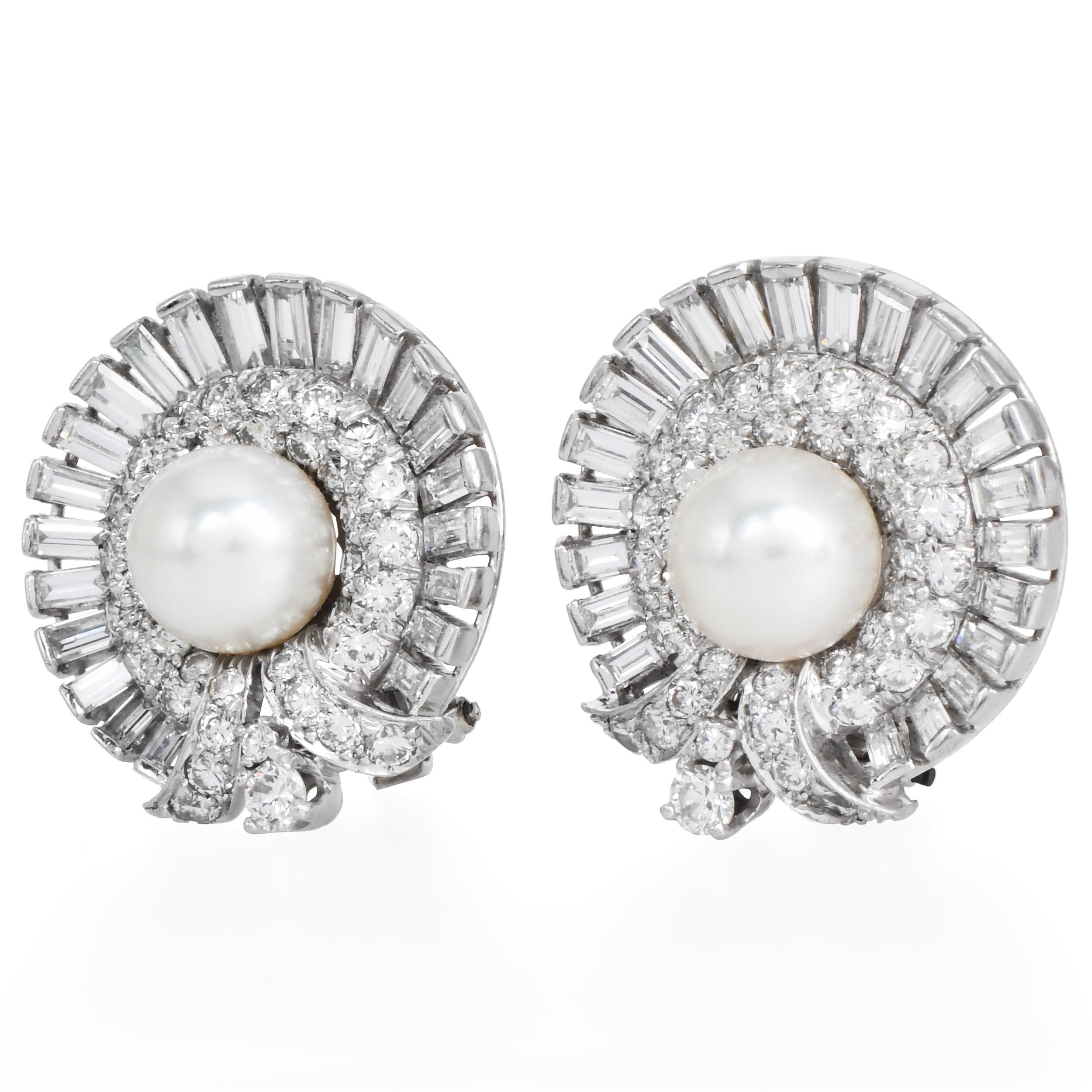 Squisiti orecchini vintage in platino con una splendida perla rotonda centrale incorniciata da una raggiante aureola di diamanti. Disegnati con un audace motivo flair, gli orecchini sono impreziositi da diamanti tondi brillanti e baguette, che