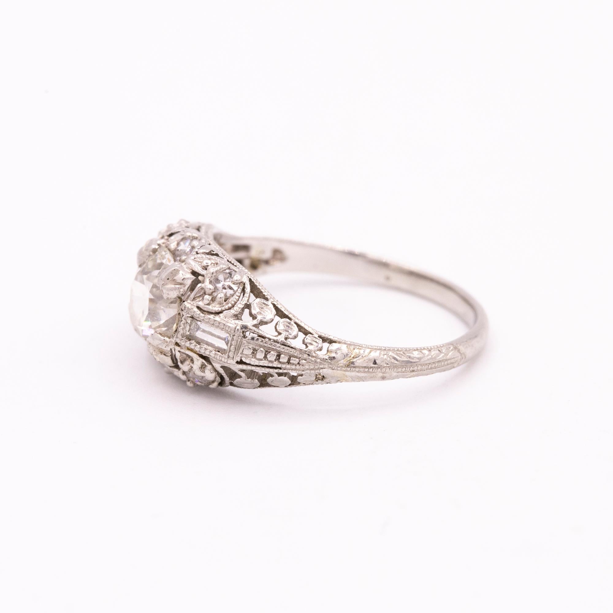 Vintage platinum diamond ring with filigree done by hand engraving. The center diamond weighs approximately 1.00 carat and the two baguette diamonds weigh a total of .36 carats. The side diamonds are G - I in color and VS in clarity. The center