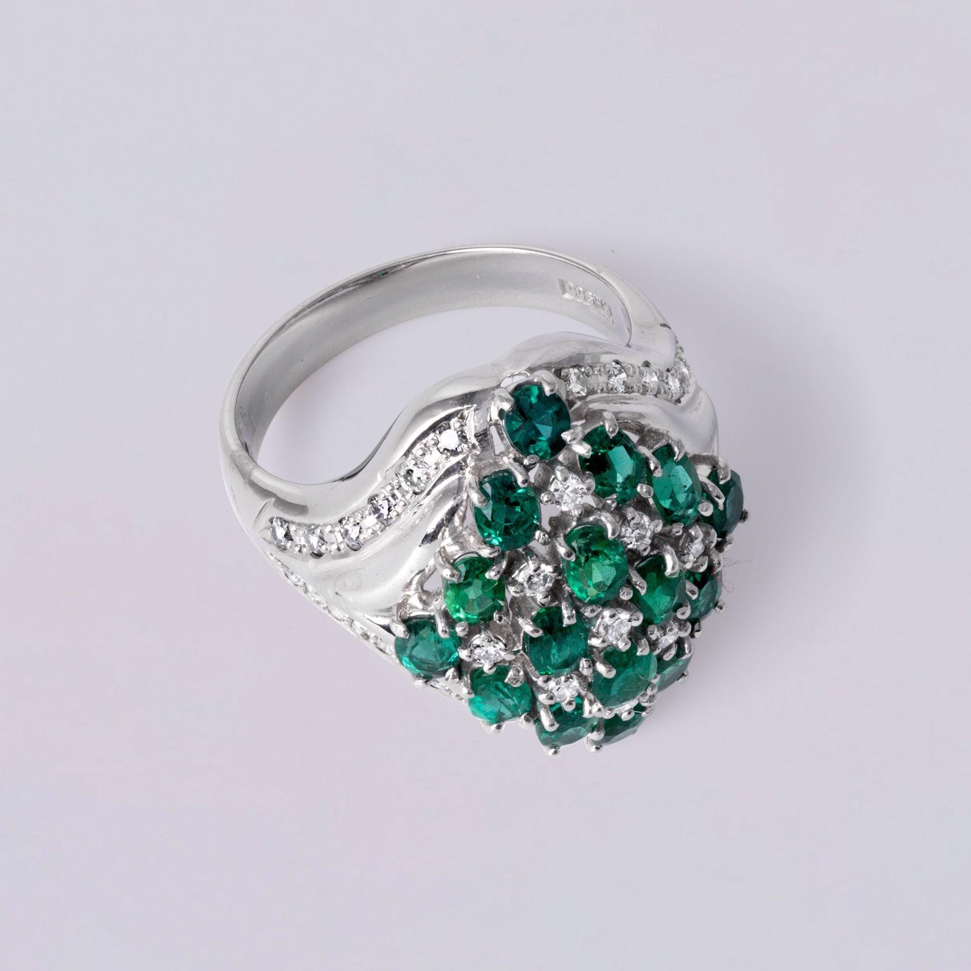 Sorprendente anillo de platino, con vívidos óvalos de esmeralda verde intenso encajados en un radiante racimo de diamantes brillantes redondos blancos. Diseñada para cautivar, esta pieza combina la elegancia atemporal con un toque