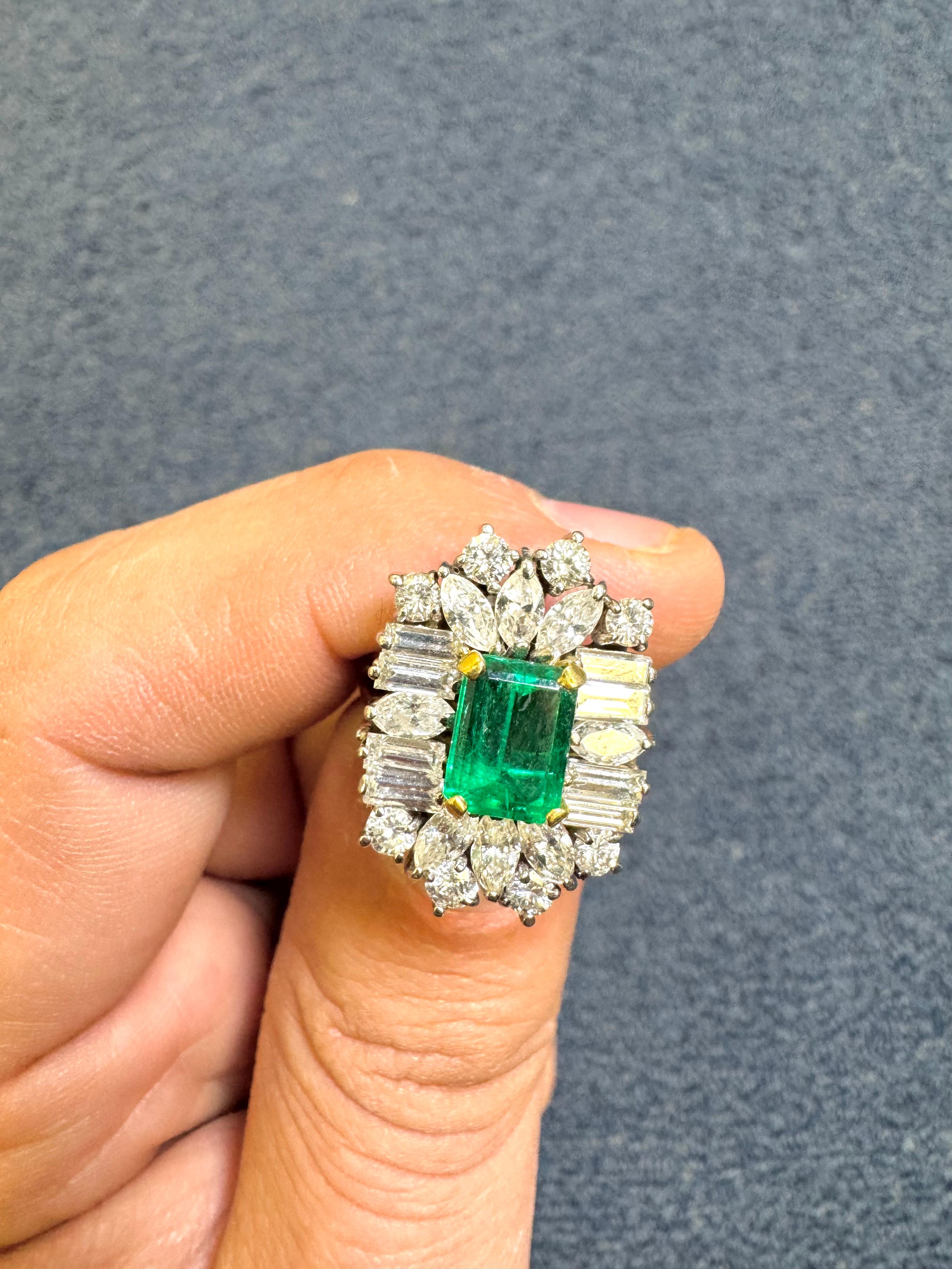 Sorprendente anillo vintage en racimo de platino que exhibe en su centro una vívida esmeralda talla esmeralda de 1,45 quilates, engastada en una montura de cuatro puntas de oro amarillo. La esmeralda está rodeada por unos impresionantes 3,25