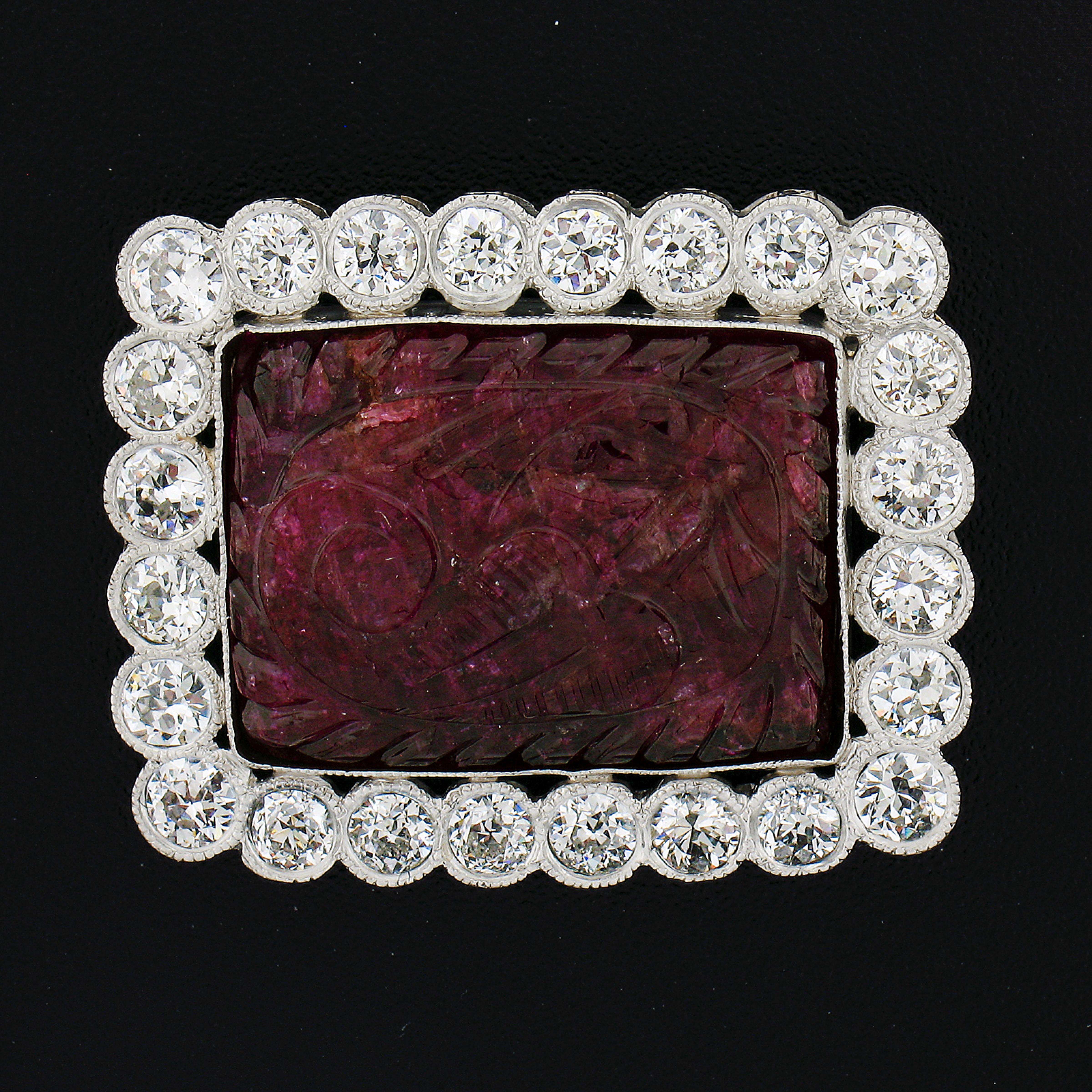 Here we have a beautiful vintage carved natural ruby brooch crafted from solid platinum. The carving features a floral pattern and it is a rectangular shaped cut. The frame is adorned with bright old European cut Milgrain bezel set throughout. This