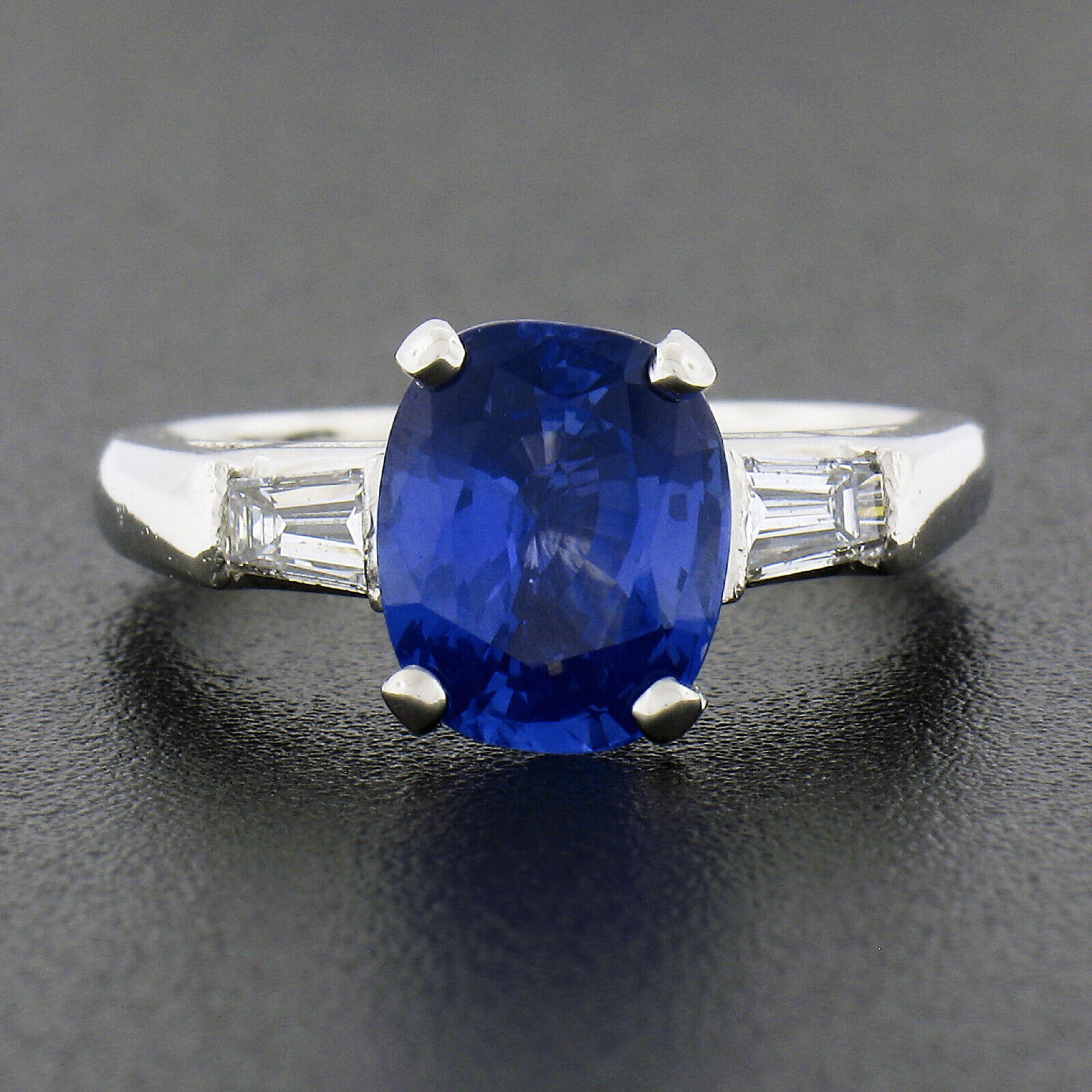 You are looking at a truly breathtaking sapphire and diamond engagement ring that is crafted in solid platinum. This vintage ring features a gorgeous, GIA certified, cushion cut sapphire solitaire neatly prong set in the center basket and flanked on