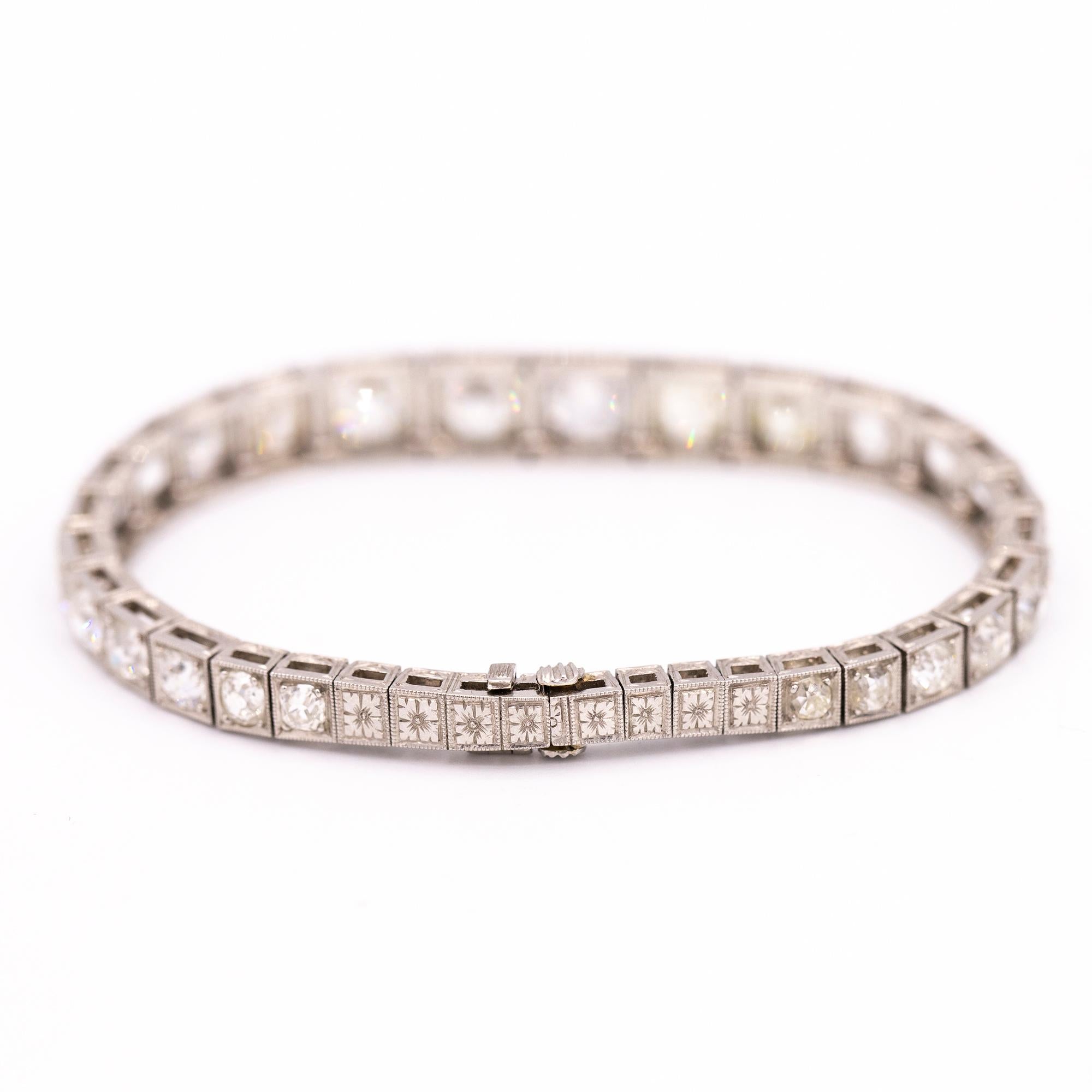Platinum hand engraved Diamond bracelet from 1910. The bracelet is set with 26 Old Mine Cut diamonds that are graduated in size. The diamonds range from F-K in color and have a total carat weight of 12.50 carats. 
