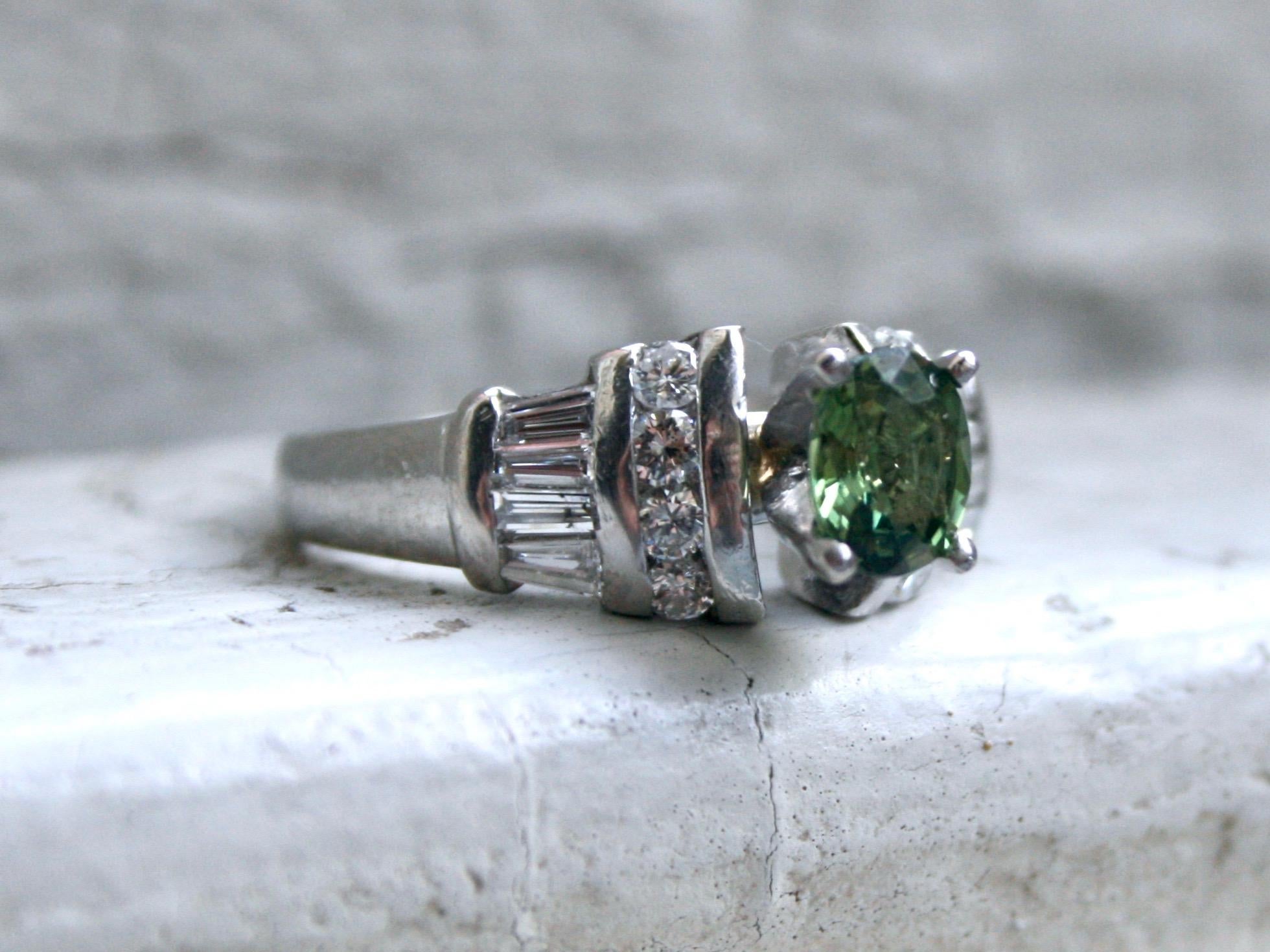 I just can't resist the classic beauty of this Beautiful Vintage Green Sapphire and Diamond Engagement Ring. Crafted in Platinum, the design features a stunning Green Sapphire Center, surrounded by Round Brilliant and Baguette Cut Diamonds. In the
