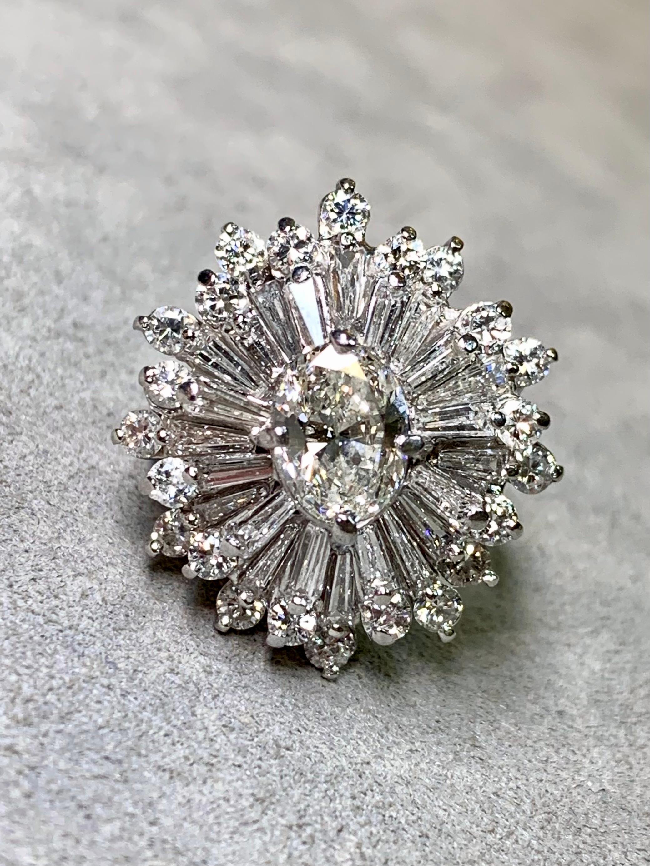 
Bague de cocktail scintillante réalisée à la main en platine et centrée sur un diamant de taille ovale d'environ 1,15 carat de couleur I et de pureté Vs1. La pierre centrale est entourée d'environ 3,45ctw de diamants baguettes et ronds. Toutes les