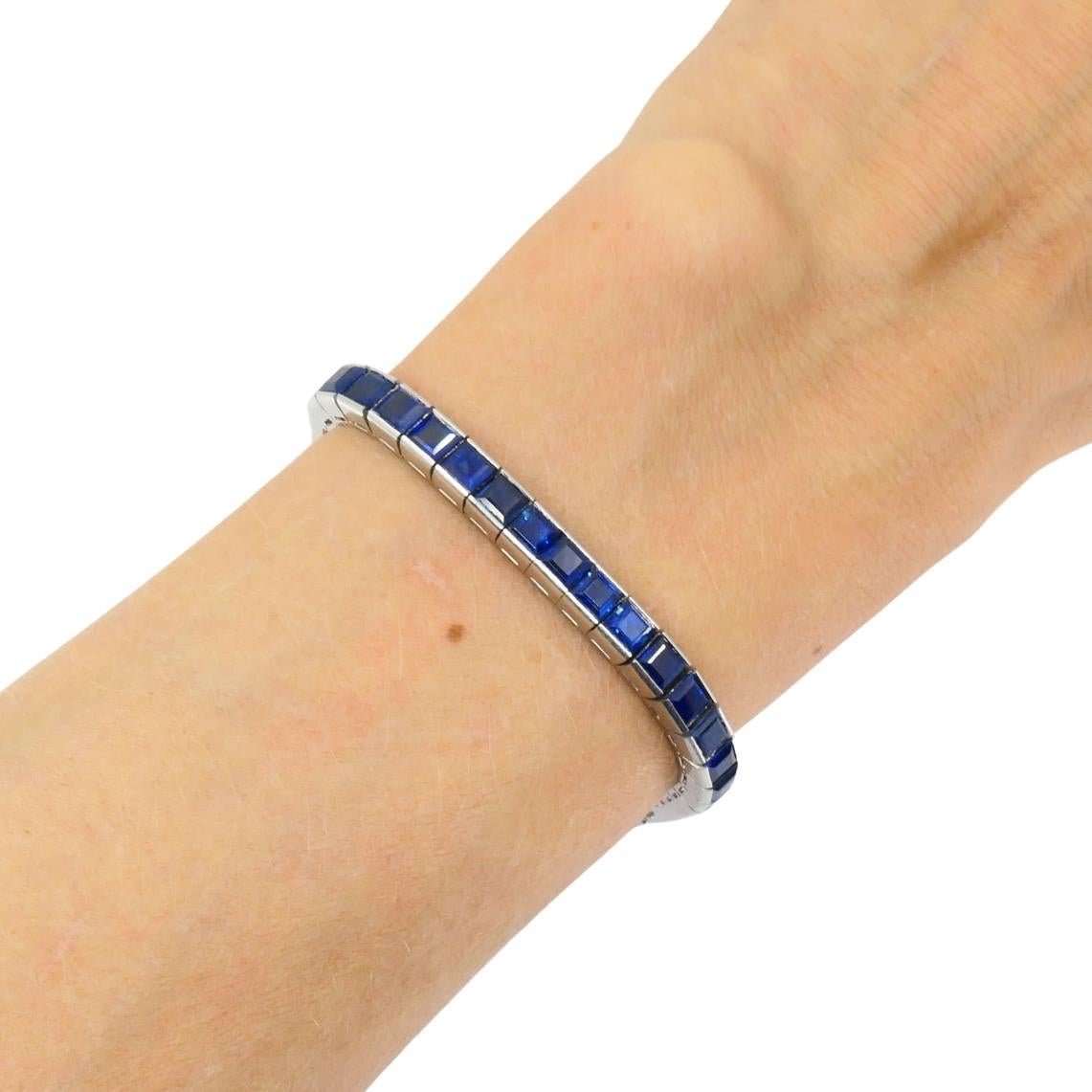 Esta pulsera tenis vintage está elaborada en platino y engastada con una hilera continua de zafiros azules de talla cuadrada. Los zafiros están engastados con precisión en eslabones de platino, creando una línea continua de azul intenso a lo largo