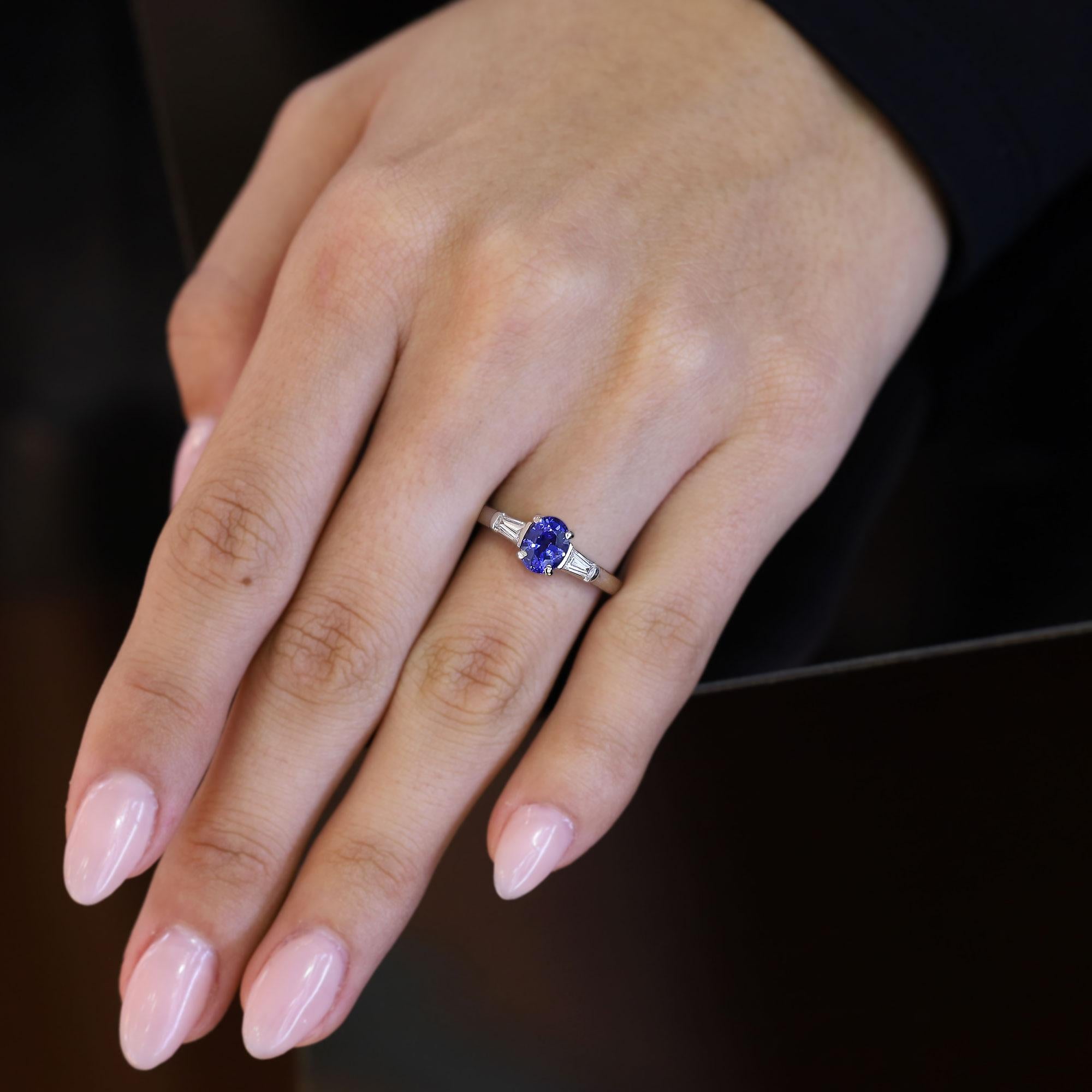 Un intramontabile anello di fidanzamento Tiffany & Co. con zaffiro e diamante. La classica composizione a tre pietre in platino è incentrata su un vellutato e vibrante zaffiro ovale blu reale da 1,17 carati ed è affiancata da una coppia di