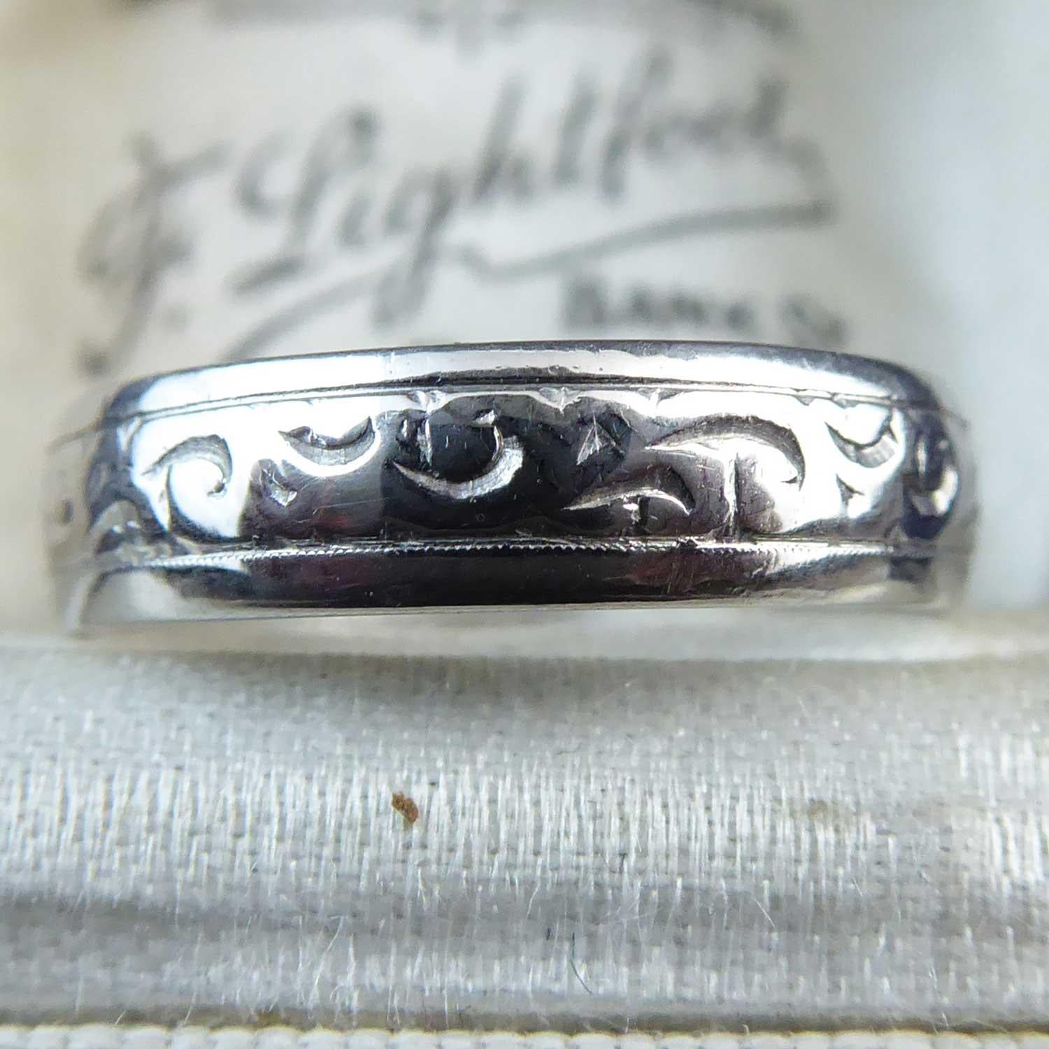 Vintage wedding ring in platinum from 1975, decorated with an acanthus leaf style engraving all the way around the centre of the band with a plain polished edge.  A slight D shaped cross section, the band measures 4.3mm wide.  Finger size 6.5