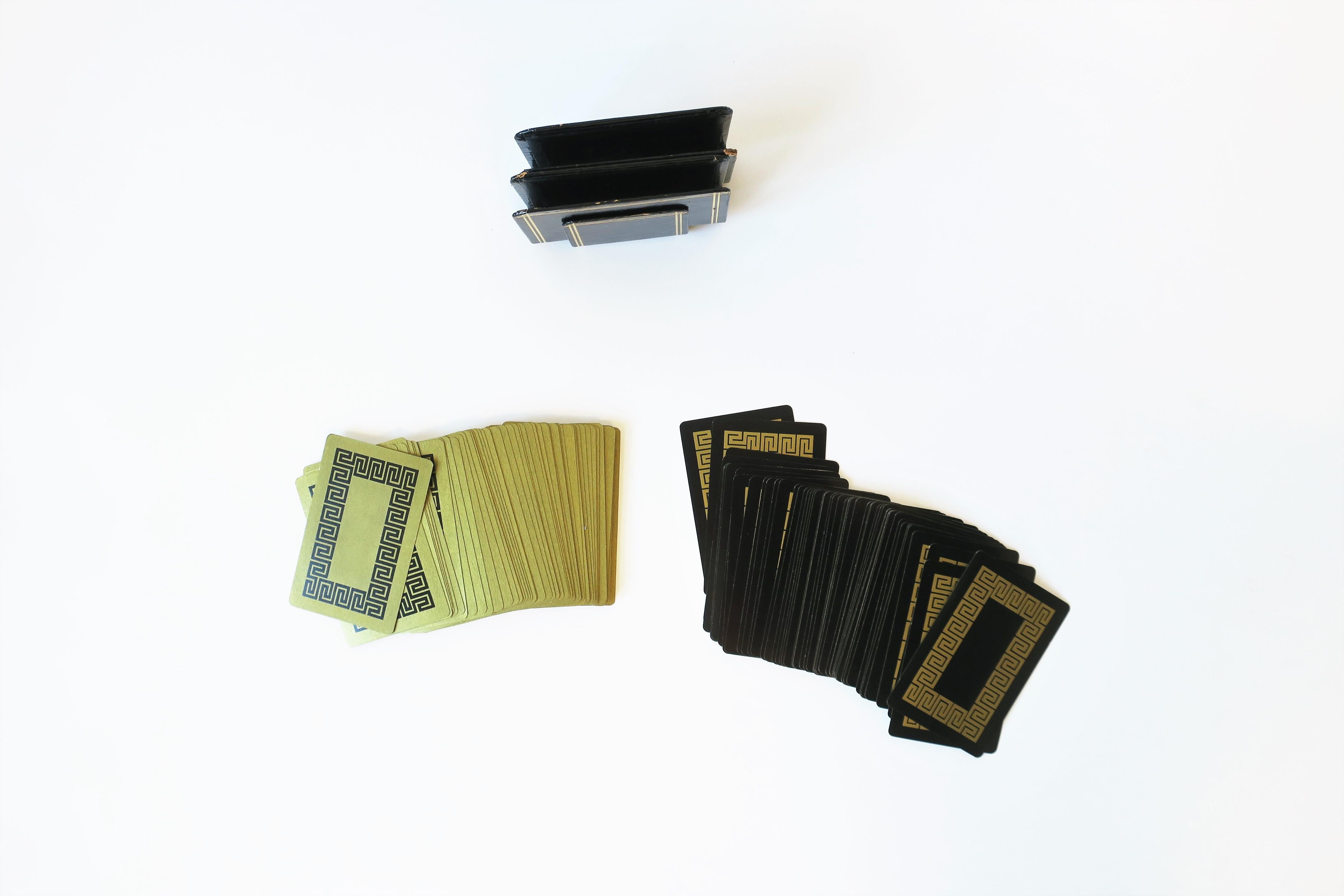 A beautiful double deck set of vintage game playing cards in black and gold with Greek-Key design, circa mid-20th century, Europe, possibly Italy. This set of two decks reside in original high-gloss black and gold embossed holders; decks sit neatly