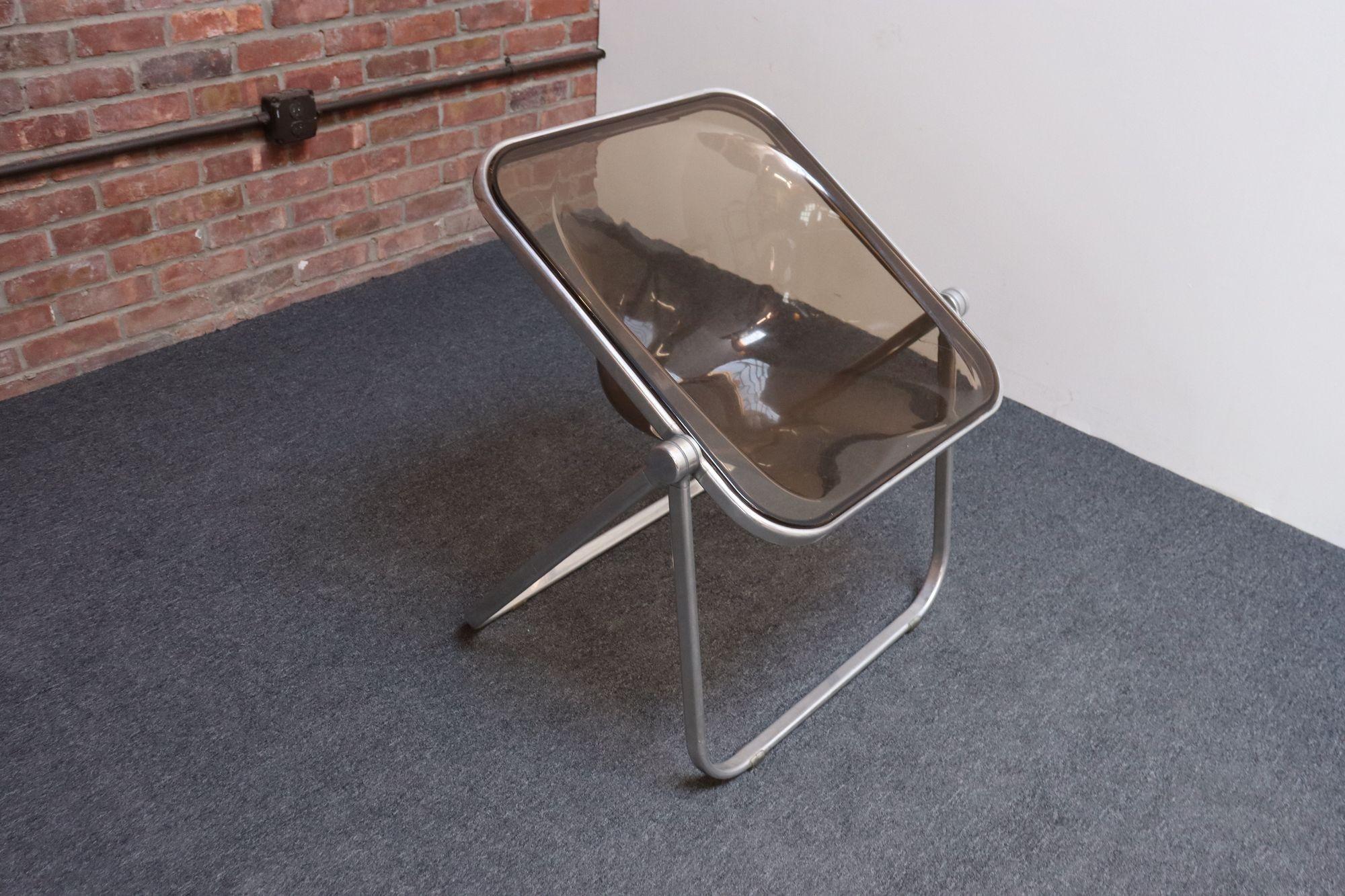 Silla de escritorio/acento Plona temprana compuesta por un asiento de acrílico ahumado moldeado y un armazón de aluminio plegable, diseñada por Giancarlo Piretti para Castelli (ca. 1970, Italia).
Plegable/apilable para guardarla cómodamente cuando
