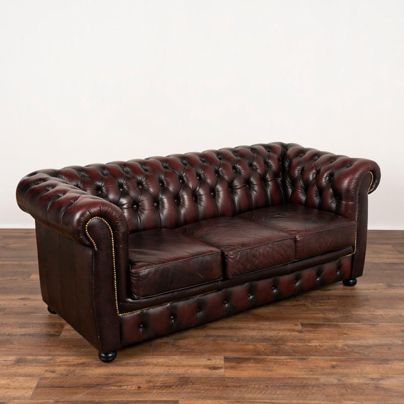 This classic 3-seat Chesterfield sofa with rolled arms and tufted back adds a vibrant touch with rich plum colored vintage leather. Please examine the close up photos to appreciate the patina of the leather, wear along the seats and original buttons