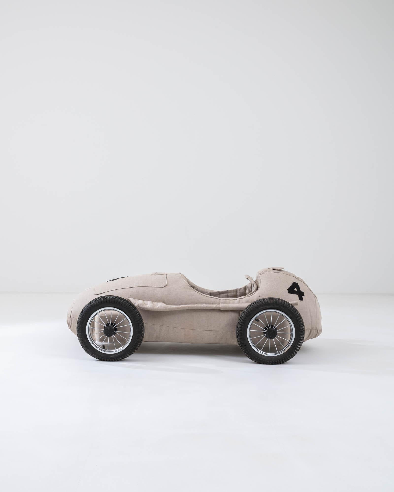 Both playful and oddly mechanical, this quirky race car is full of character and witty design. Lovely design-inspired details such as a sewn hood and side exhaust pipes exemplify an engaging design sense as well as a lighthearted celebration of