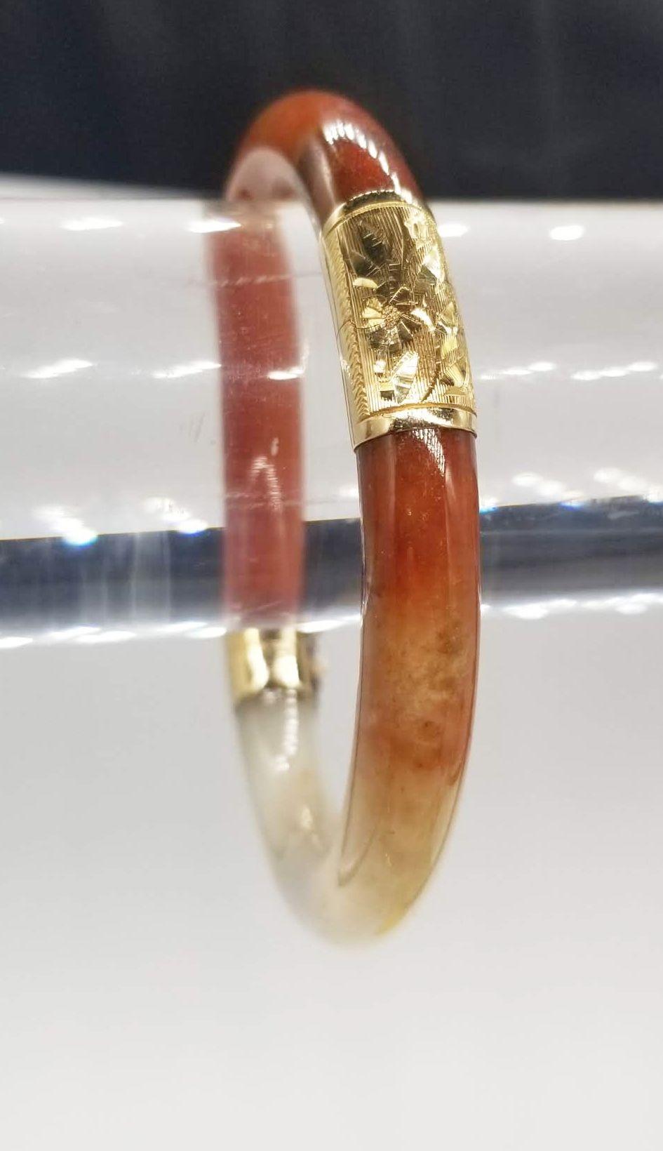 This exquisite vintage bangle bracelet is a true statement piece, featuring a captivating combination of polished red-orange agate and luxurious gold accents. The agate showcases a stunning play of colors, transitioning from deep red and orange