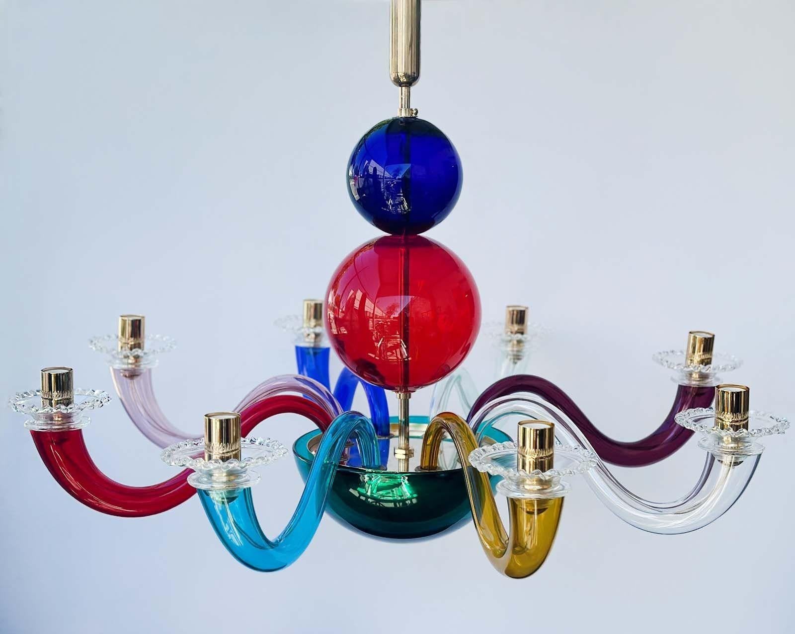 Vintage Italian Murano glass and brass chandelier designed in 1946 by Gio Ponti and manufactured by Venini, consisting of a center semicircle globe and two center colorful glass balls, along with eight arm lights. Each arm of the chandelier features