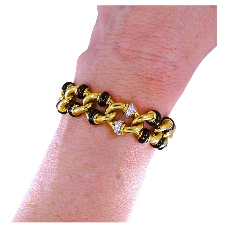 Ein Vintage-Armband von Pomellato aus 18 Karat Gold mit Granat und Diamanten.
Das Armband besteht aus leicht gedrehten Gelbgoldgliedern. Vier Glieder sind mit Weißgold und Diamantrondellen verziert. Jedes der übrigen Glieder ist mit zwei
