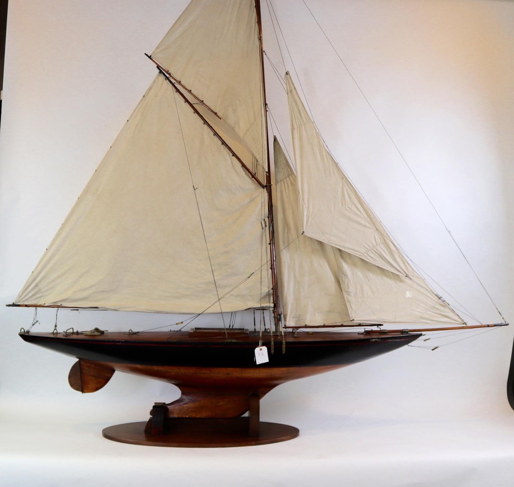 Large eight foot vintage pond yacht of the sloop hornet. With planked hull and varnished deck, a full suite of sails and heavy lead keel. Set onto a custom wood stand. Weight is 68 pounds.