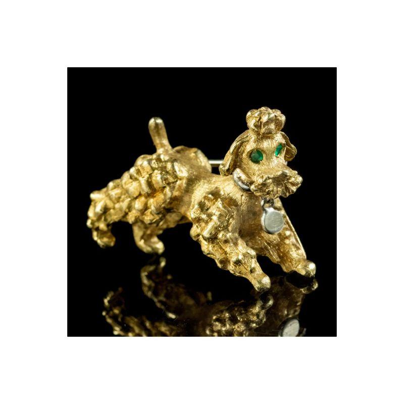 An adorable vintage poodle brooch made in Italy in the mid 20th century. The head is set with green, emerald eyes and features a collar around the neck complete with a dangling name tag. 

It’s crafted in 18ct yellow gold and modelled in a playful,