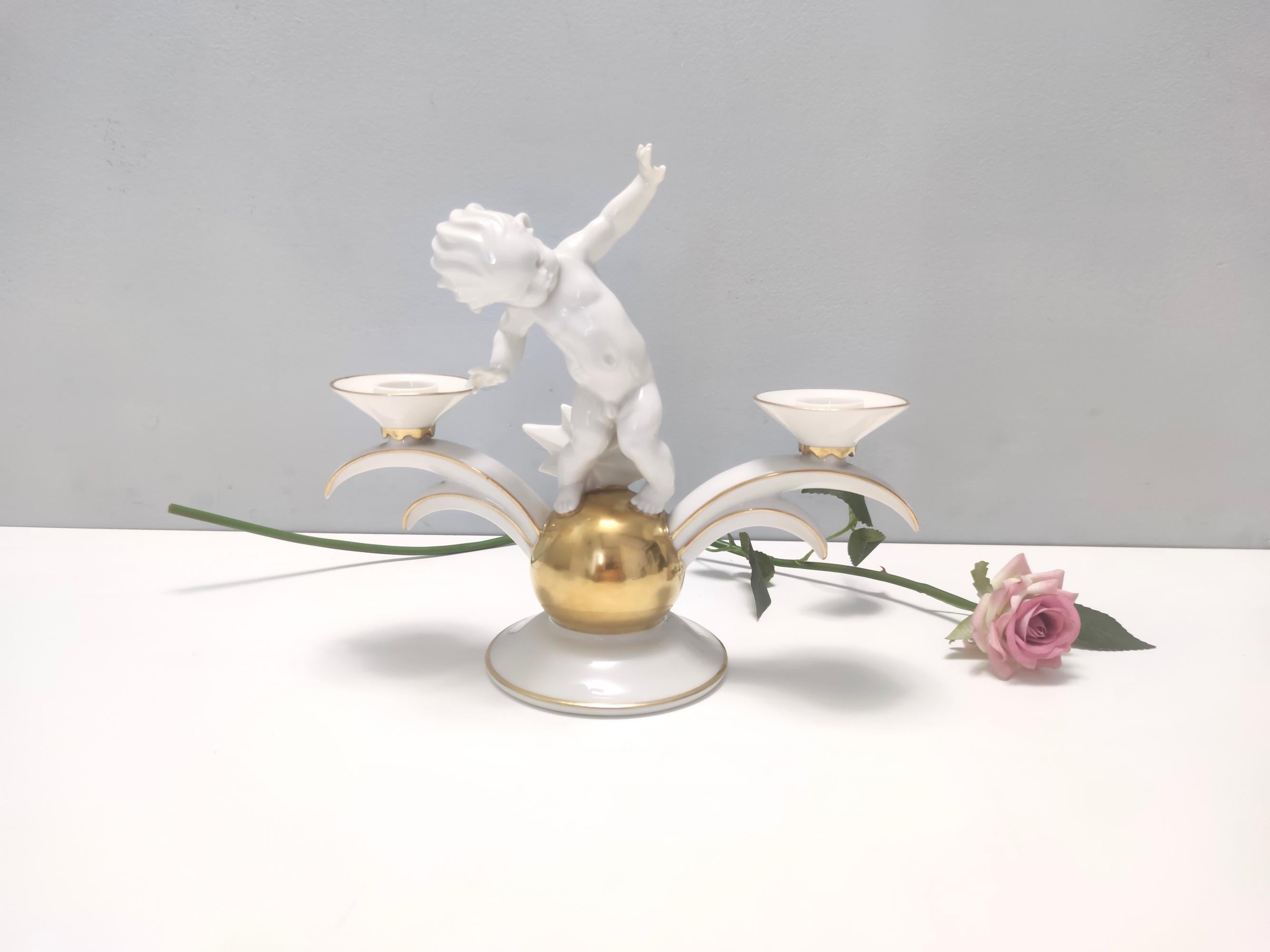 Made in Germany, 1930s. 
This high-quality two-arm candle holder is made in white and gold glazed porcelain by Karl Tutter for Hutschenreuther.  
It is. vintage piece, therefore it might show slight traces of use, but it can be considered as in