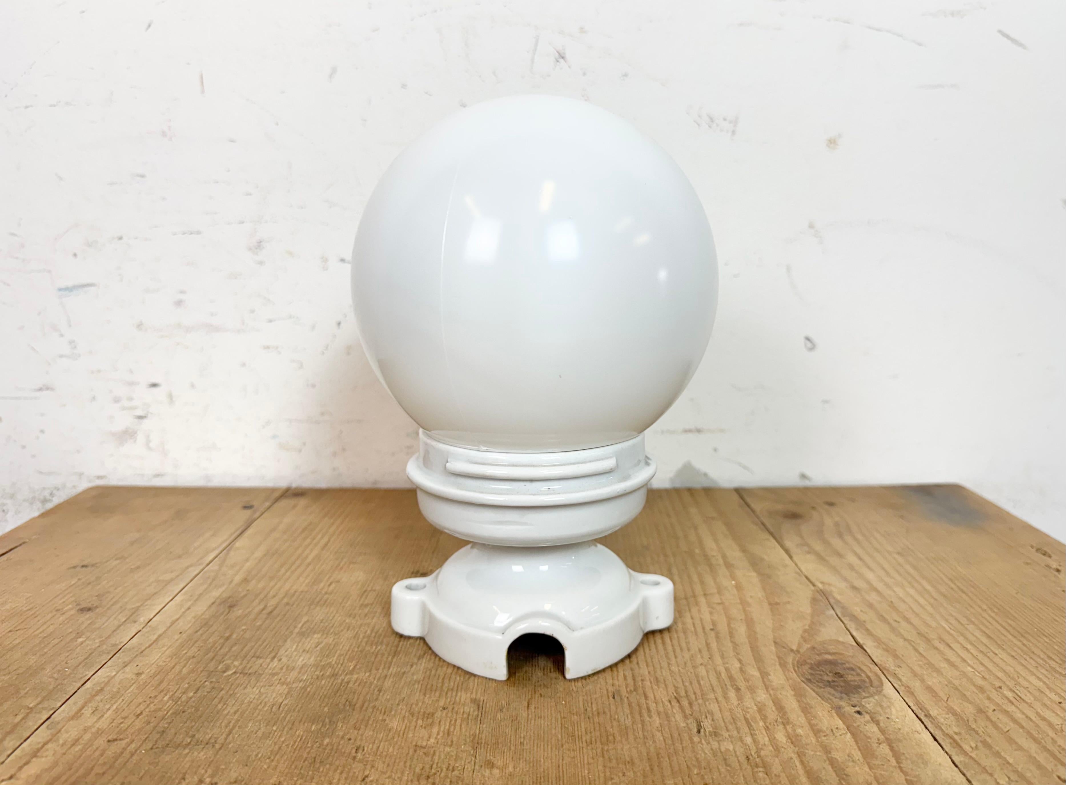 Plafonnier industriel vintage fabriqué dans l'ancienne Tchécoslovaquie dans les années 1950. Elle est dotée d'une fixation au plafond en porcelaine blanche et d'un couvercle en verre de lait. La douille est compatible avec les ampoules standard