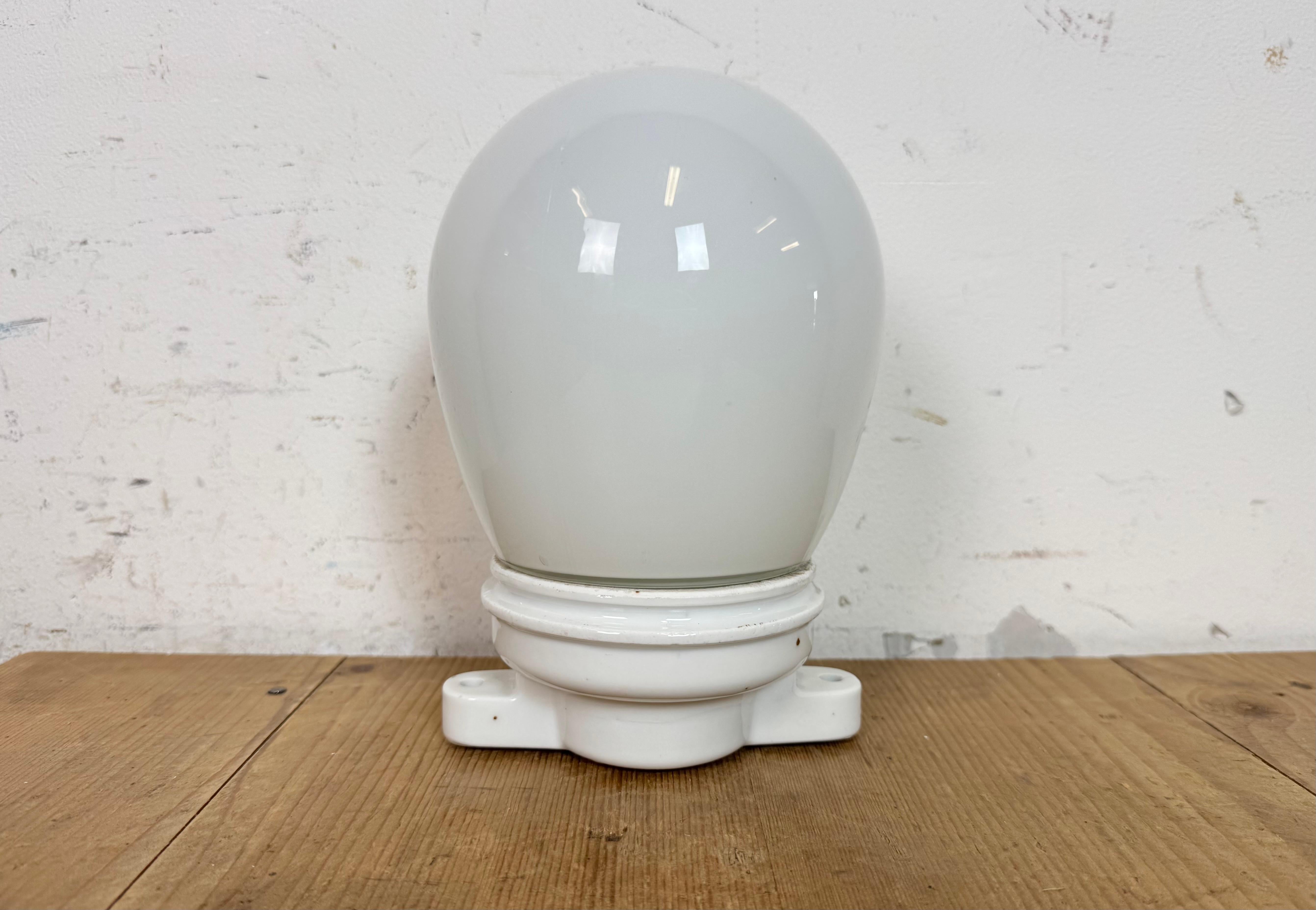 Vintage-Industrie-Deckenleuchte, hergestellt in der ehemaligen Tschechoslowakei in den 1950er Jahren. Sie hat eine Deckenhalterung aus weißem Porzellan und eine Abdeckung aus Milchglas. Die Fassung ist für Standard-Glühbirnen E27/E 26 geeignet.