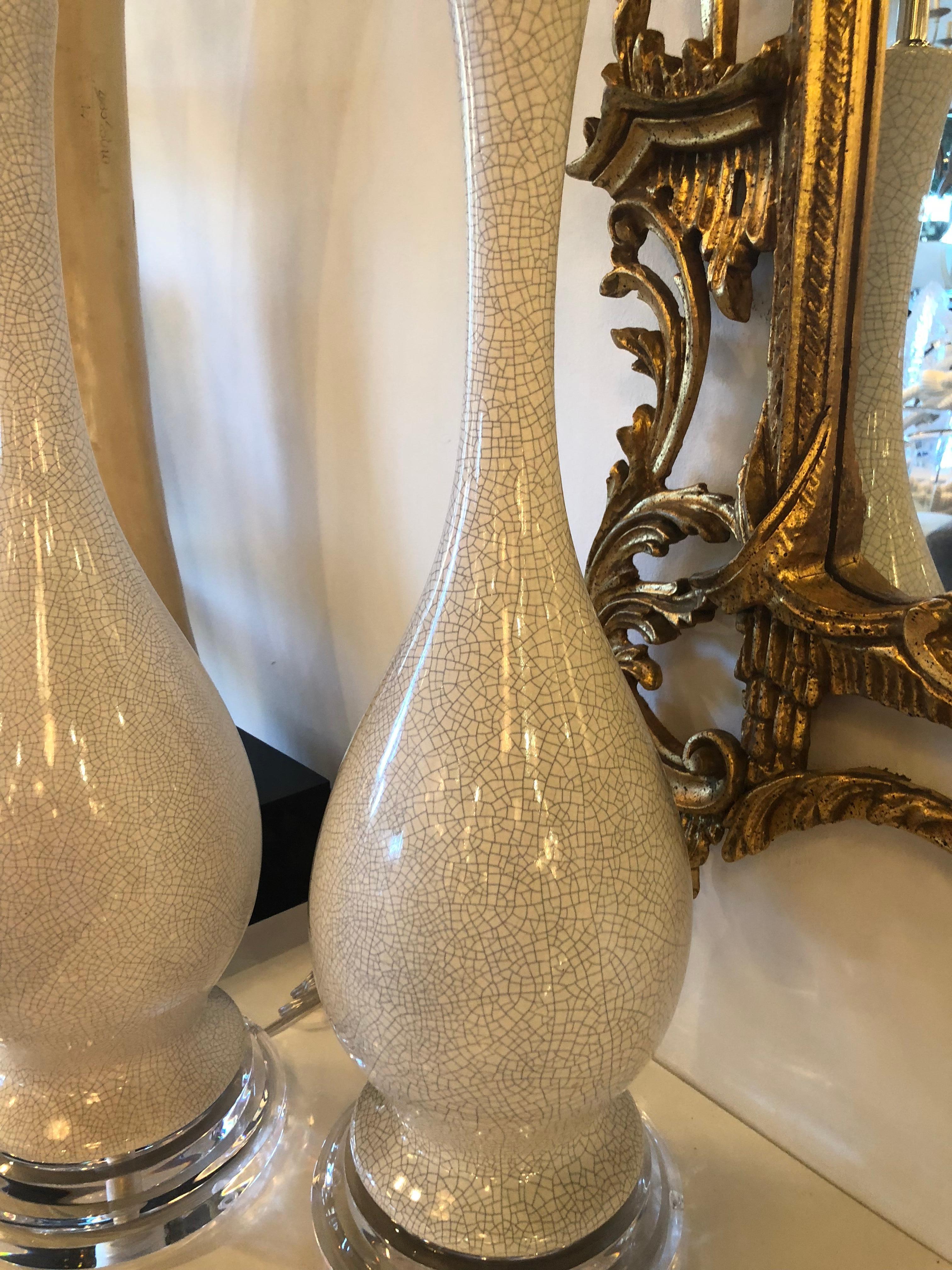 Vintage pair of crackle glaze porcelain table lamps. Grey crackle on white lamps. Newly wired, new chrome hardware, Lucite base and finial, 3 way light.
Measures: 37” tall to top of finial.