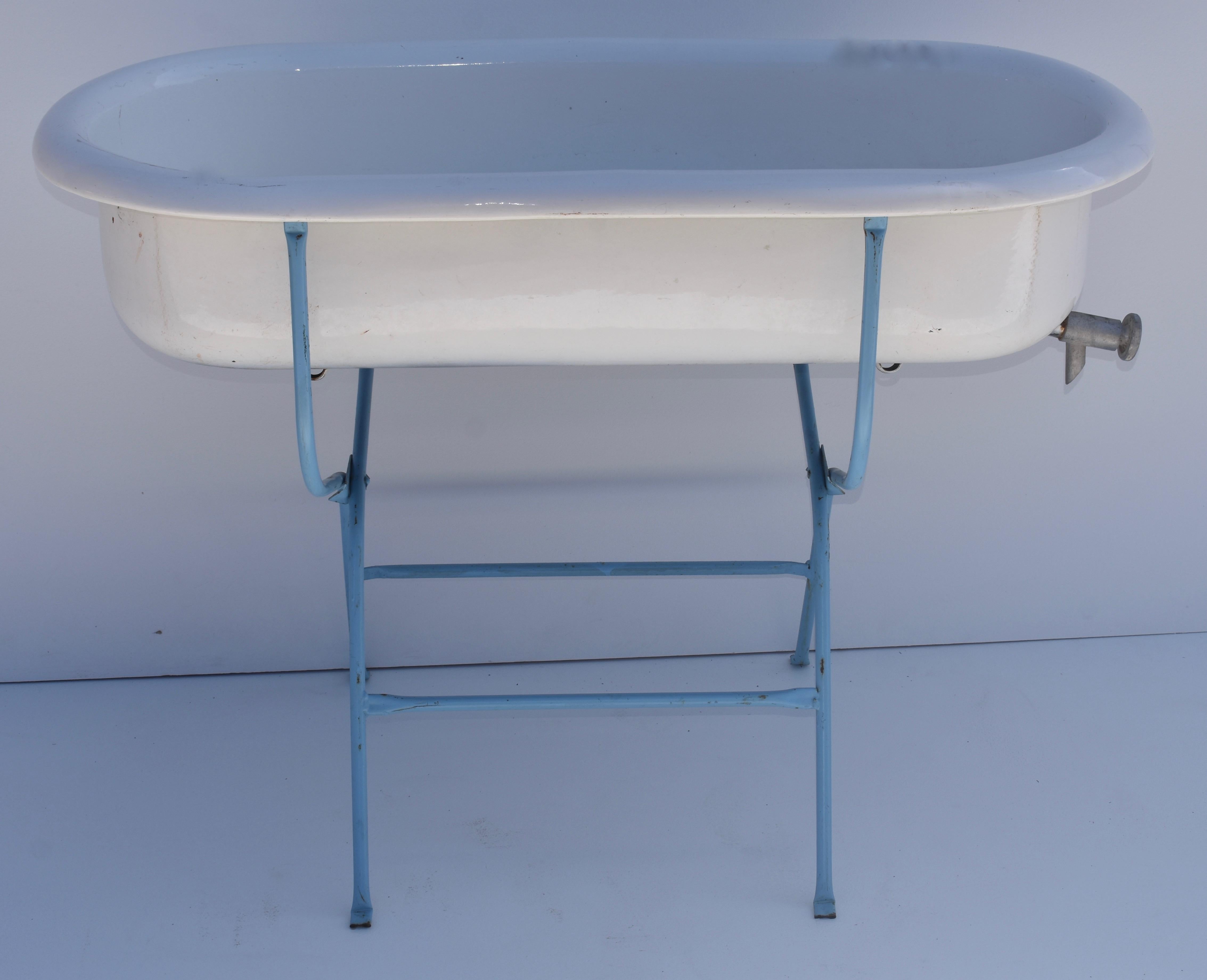 This is a delightful porcelain enameled baby bath by Lampart of Hungary, mounted on an original repainted folding wrought iron stand. With summer approaching it would be great filled with bottles of beer or wine on ice, or perfect as a planter or