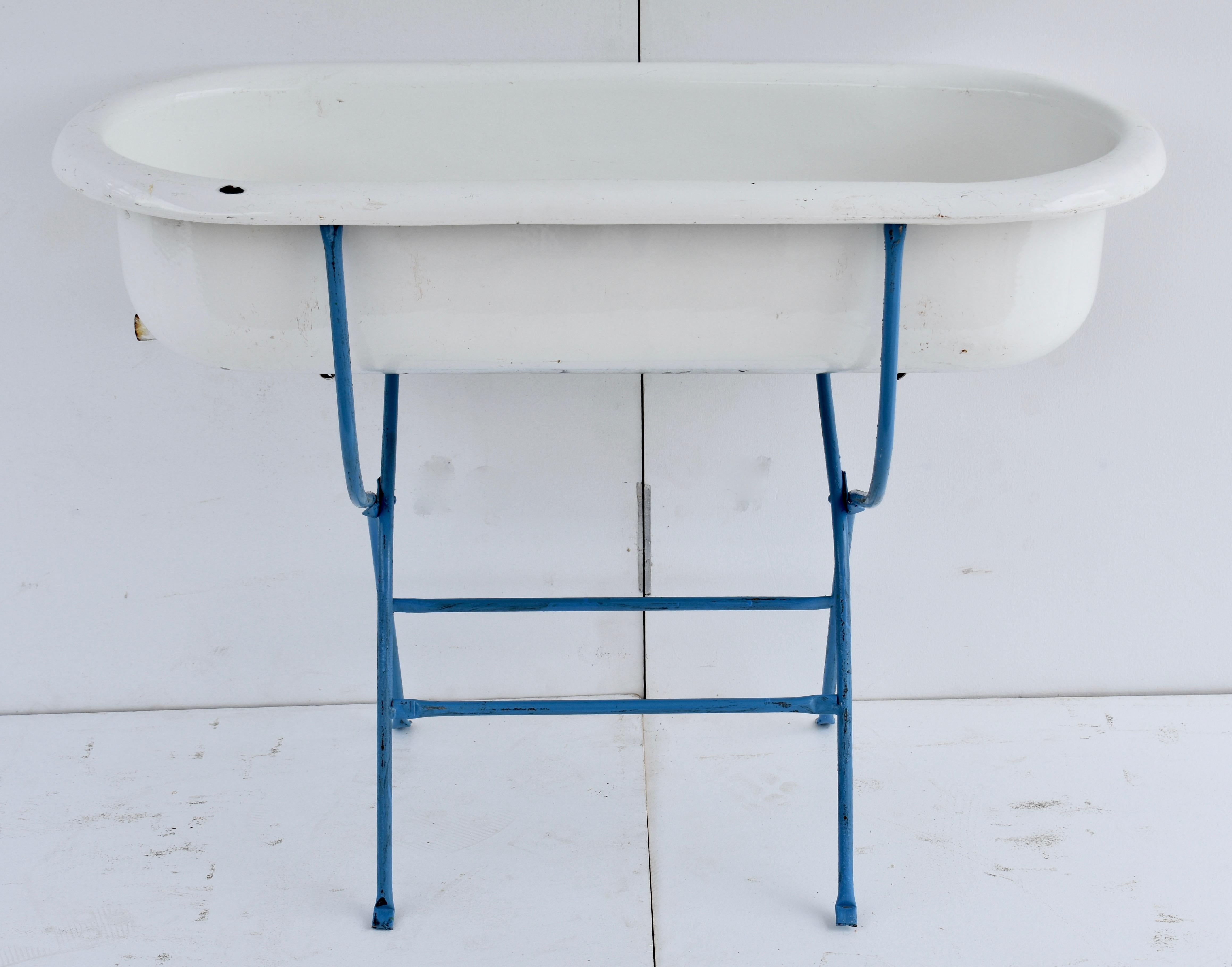 This is a delightful porcelain enameled baby bath by Zim oF Hungary, mounted on a repainted folding wrought iron stand. When summer returns it would be great filled with bottles of beer or wine on ice, or perfect as a planter or other outdoor