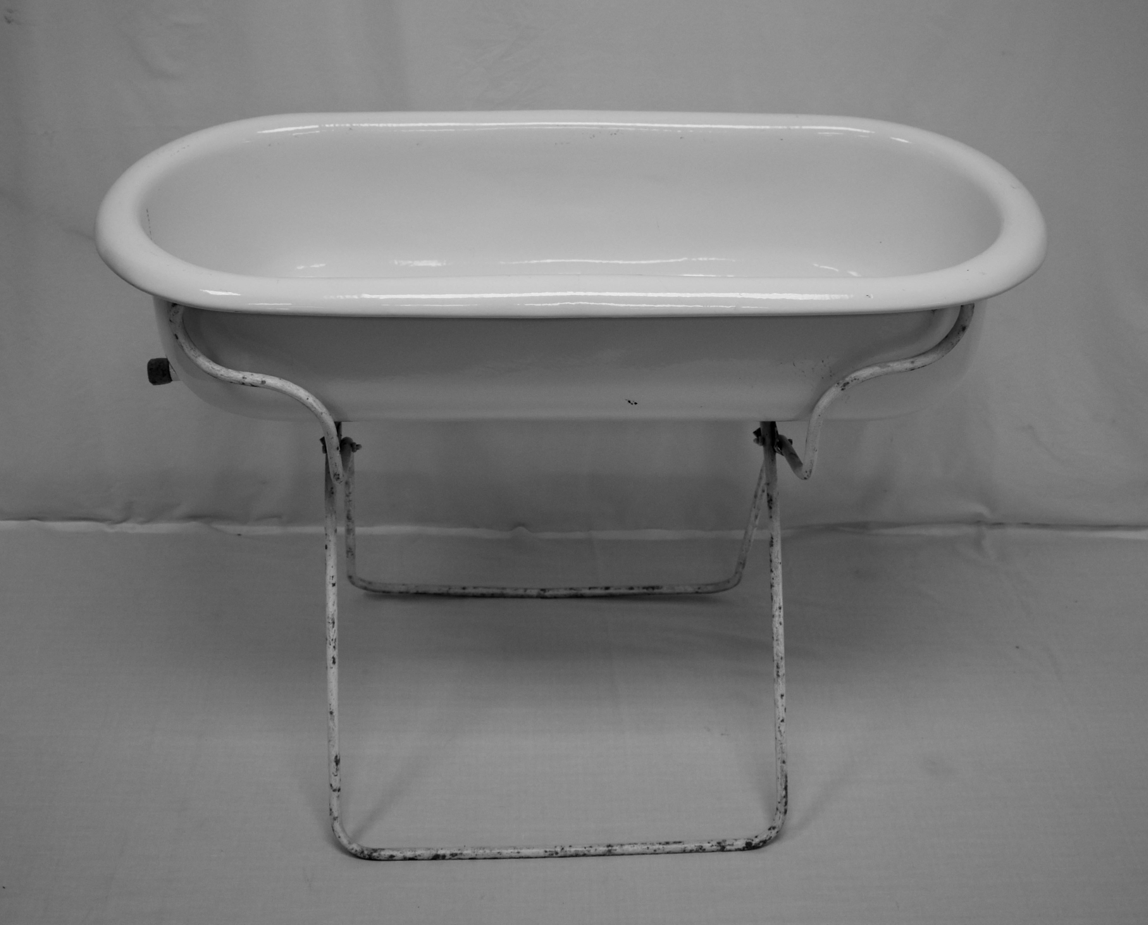 This is a vintage porcelain enamel baby bath on its original wrought iron folding stand. These are great for putting beer or wine on ice for a party, for planting and landscaping, or even for bathing the baby. This piece has a cork to replace the