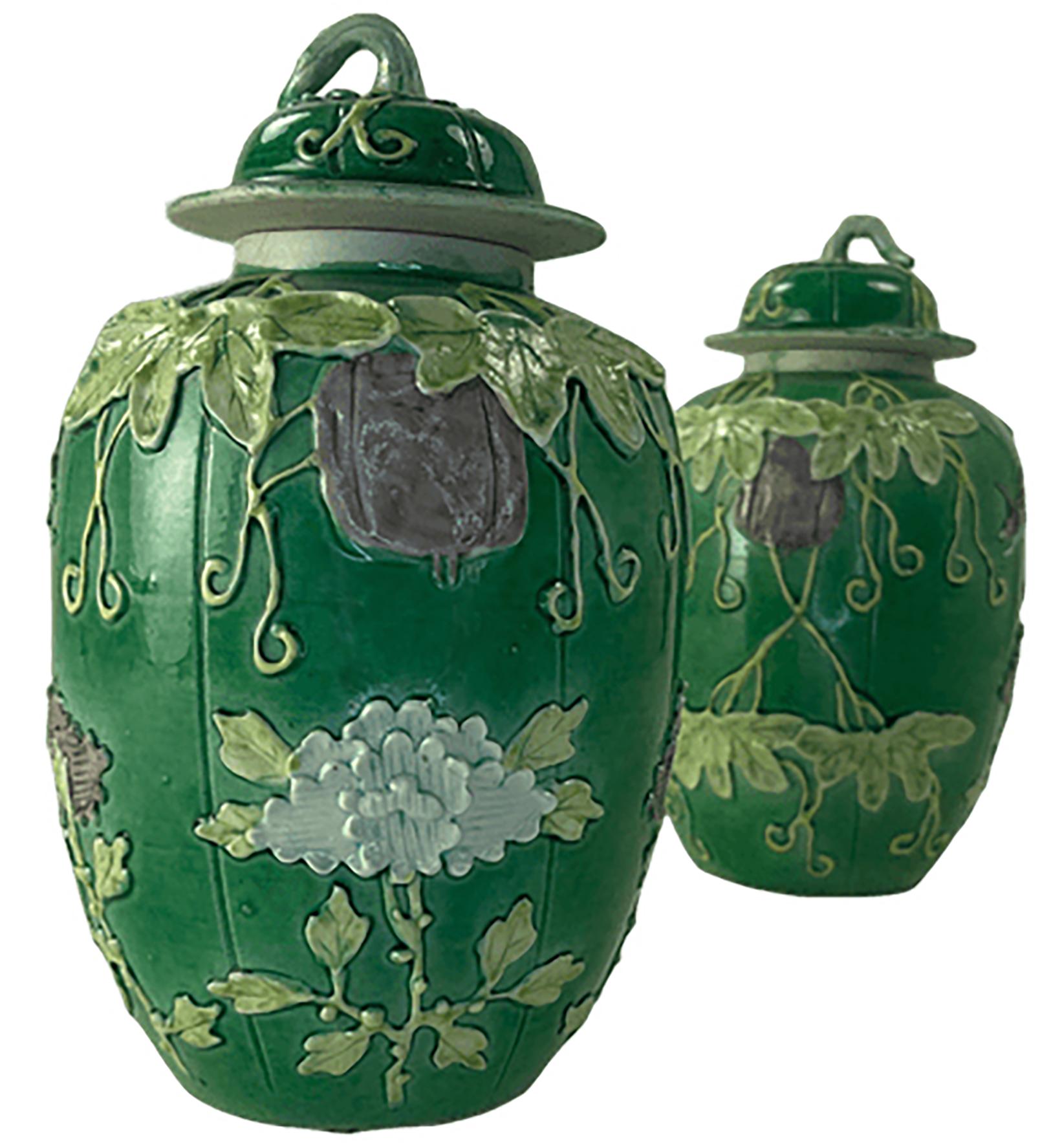 A pair of beautiful green glazed lidded vintage porcelain ginger jars. Unmarked on the bottom. Green vines and foliage are hand sculpted as dimensional features on the side of the jars with some light purple flowers included. Possibly from China,