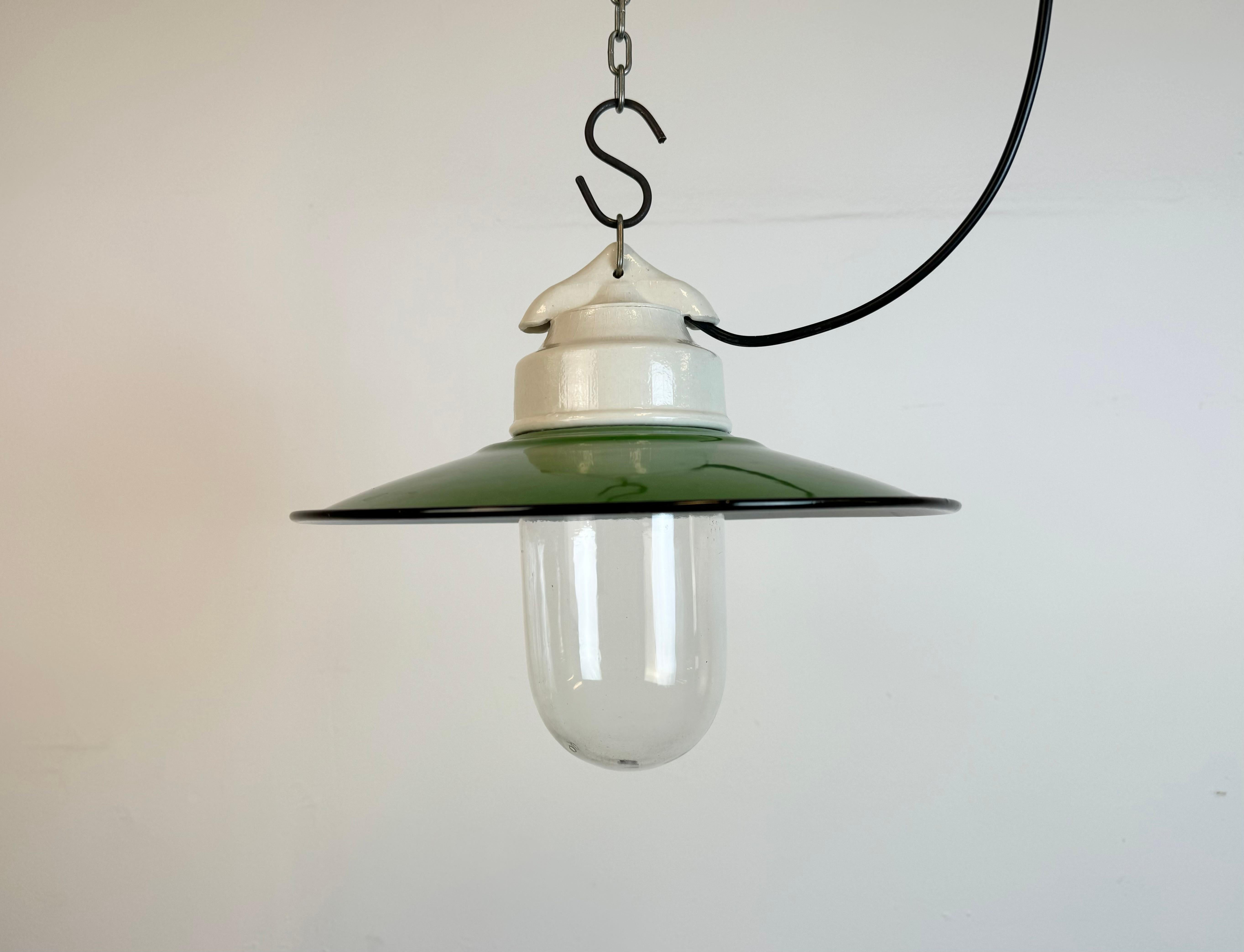 Vintage industrial light made in former Czechoslovakia  during the 1970s. It features a green enamel shade with white enamel interior ,a porcelain top and a clear glass cover. The socket requires standard E27/ E26 light bulbs. New wire. The weight