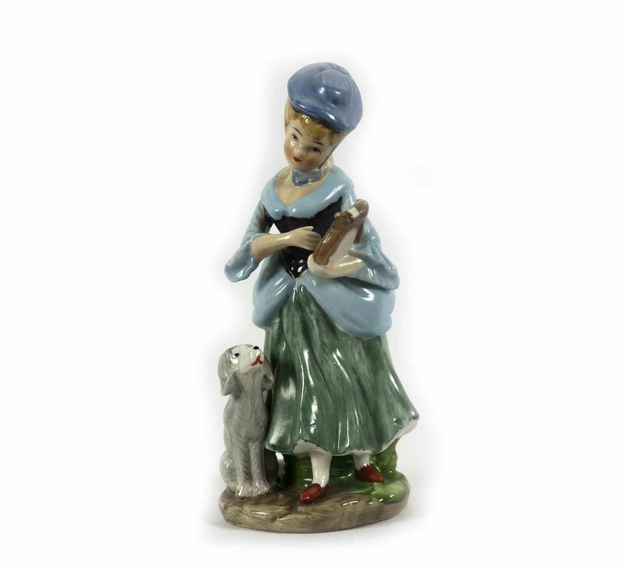 Vieille sculpture en porcelaine d'une dame avec un chien est un objet décoratif original réalisé par un artiste anonyme dans la moitié du 20ème siècle. 

Objet décoratif en porcelaine représentant une jeune fille avec un chien et une lyre dans les