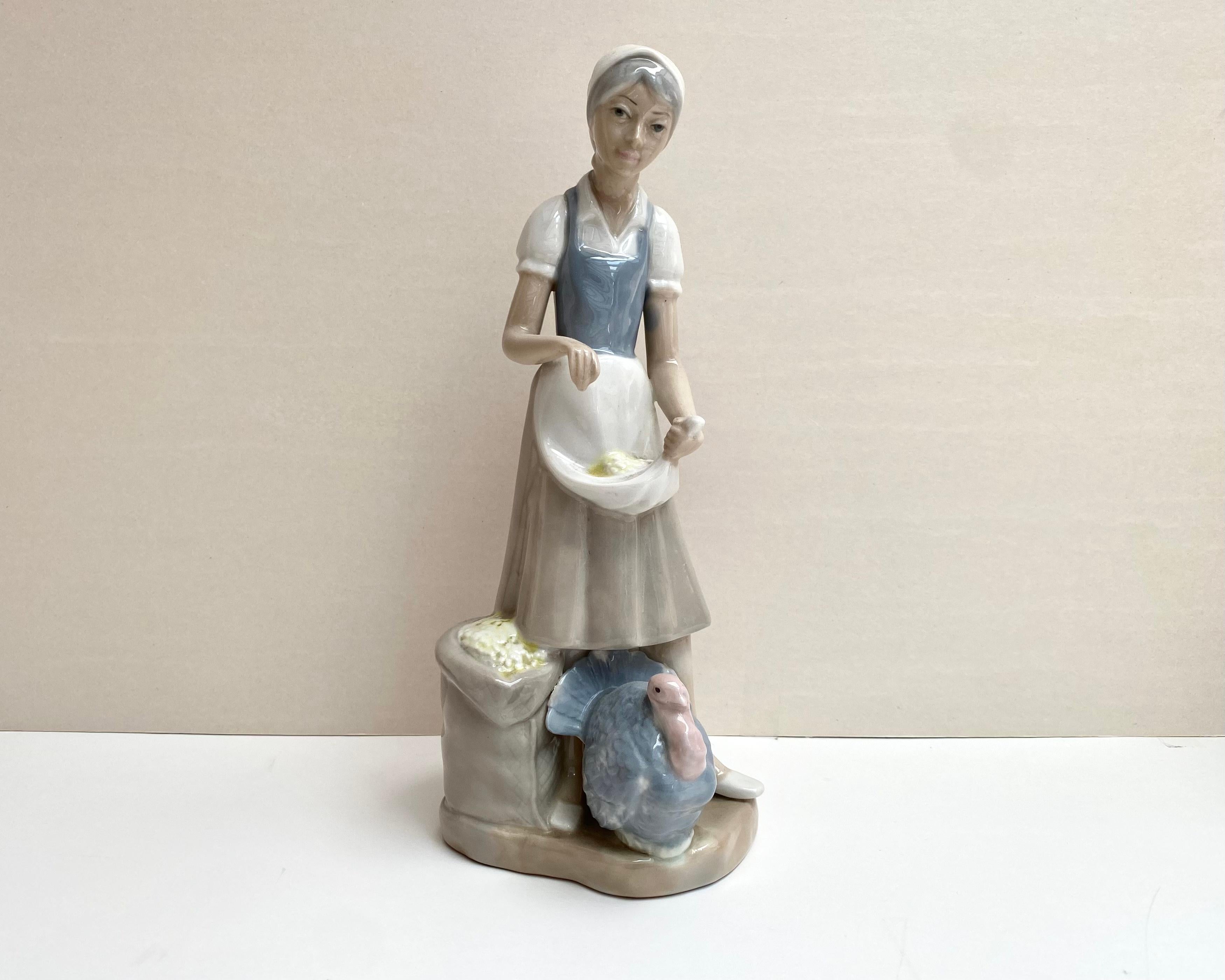 Nicely hand painted fine collectible Spanish figurine with good form and colors from the old spanish manufactory Casades known for the production of porcelain figurines since 1815.

Porcelain peasant girl with turkey. The girl holds in her apron