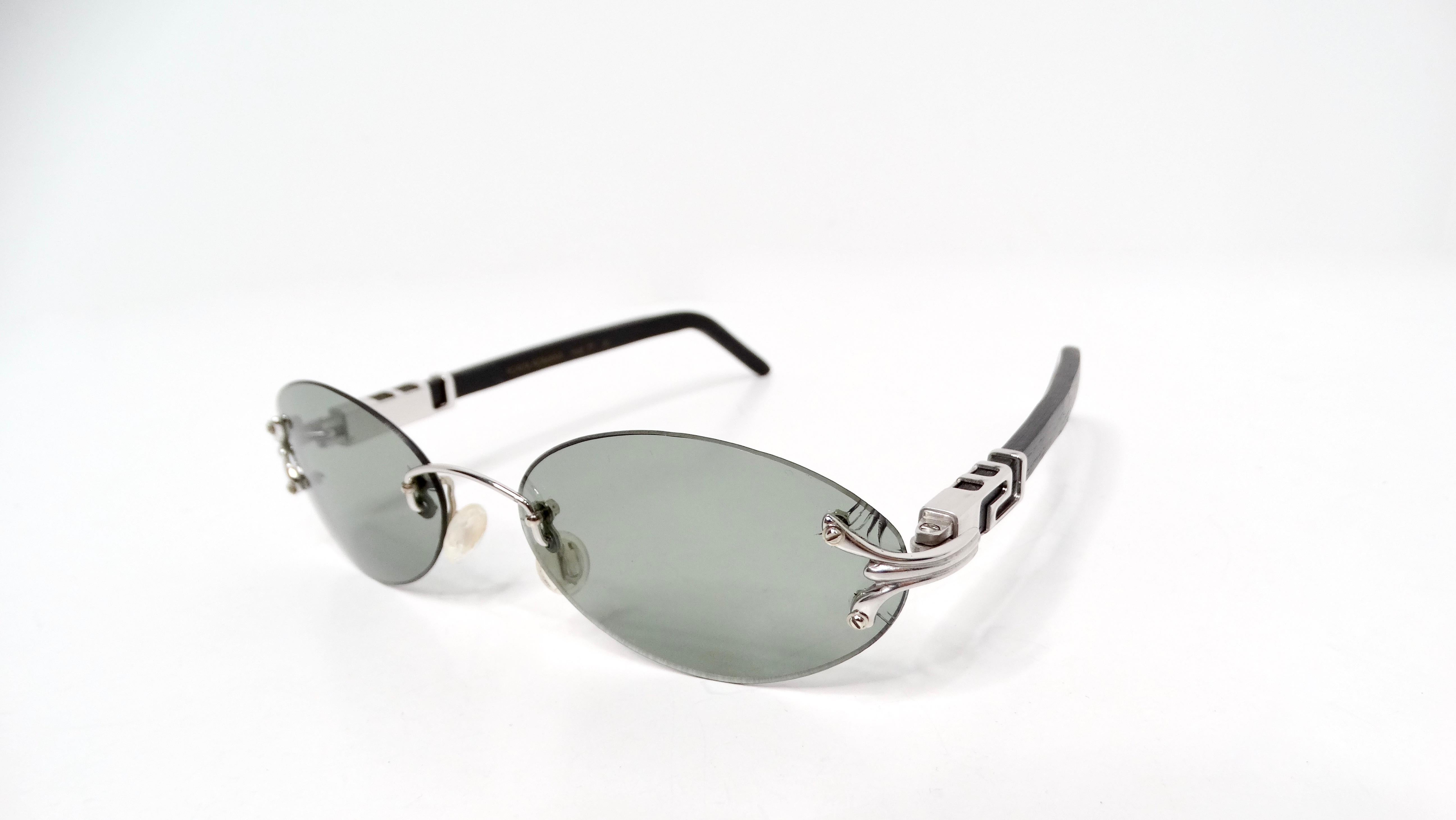 Voici les lunettes de soleil ovales sans monture Vintage Porta Romana, faites à la main, en noir et argent, une fusion saisissante d'élégance et de style rétro. Ces lunettes de soleil exquises sont dotées de tiges en bois uniques qui non seulement