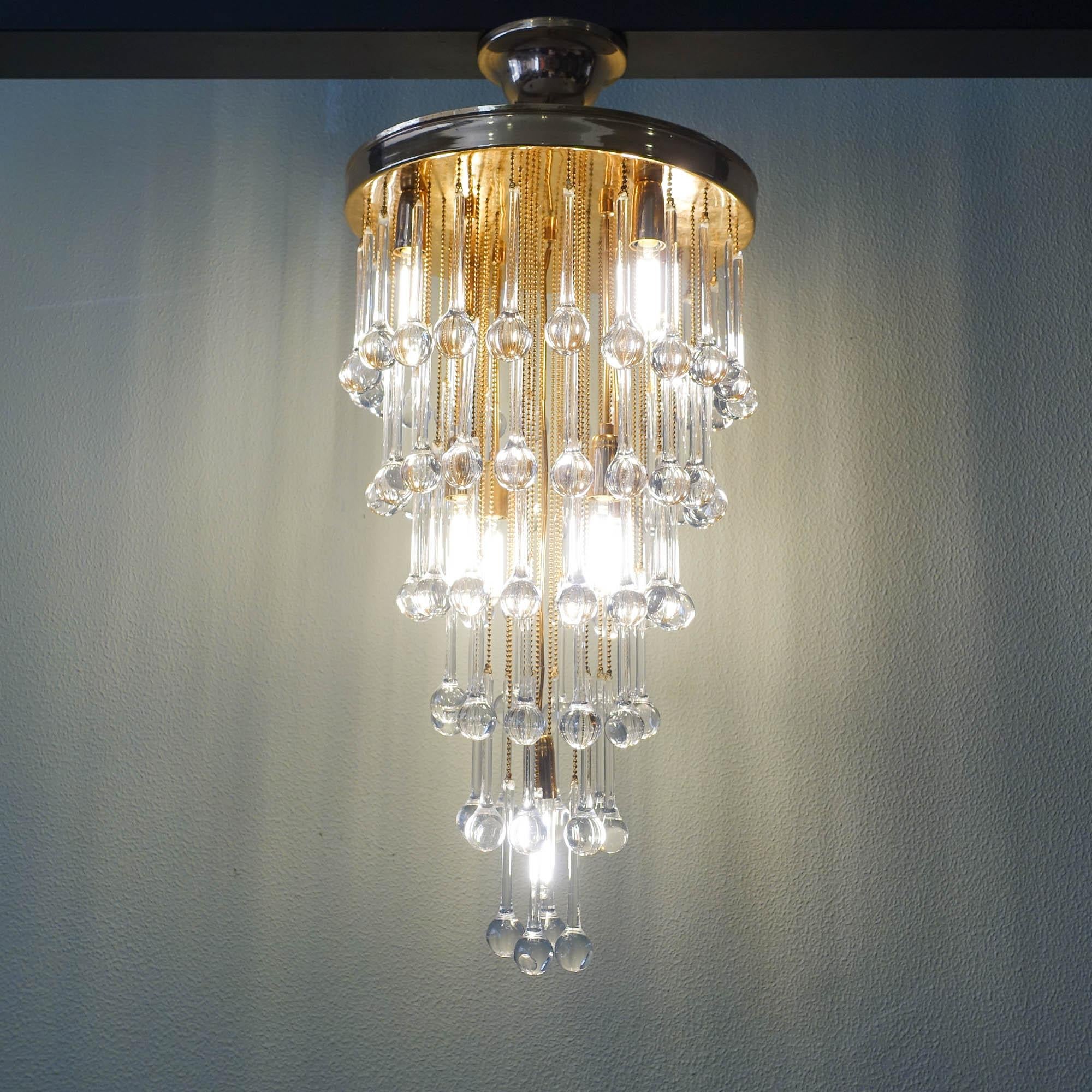 This chandelier was designed and produced by Cristaluz, in Portugal, during the 1970's. The design is very similar to the ones produced in Italy by Venini. It features a brass plate were dozens of crystal drops fall creating a layering effect with