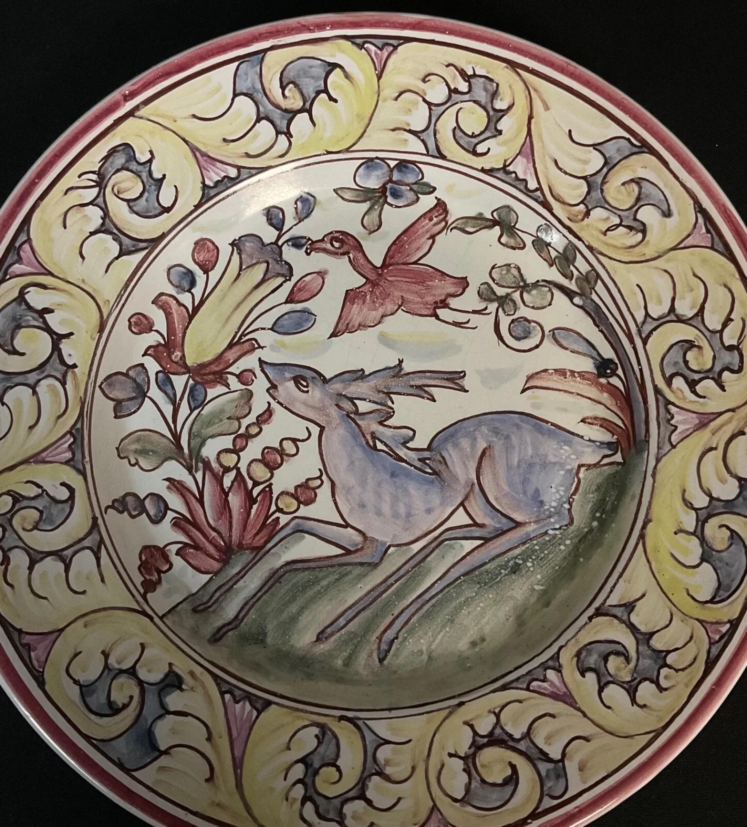 Questo piatto decorativo portoghese d'epoca, meravigliosamente vivace e affascinante, è dipinto a mano con un vivace motivo floreale e animale. Originario del Portogallo, questo piatto presenta uno stile di arte popolare caratterizzato da colori