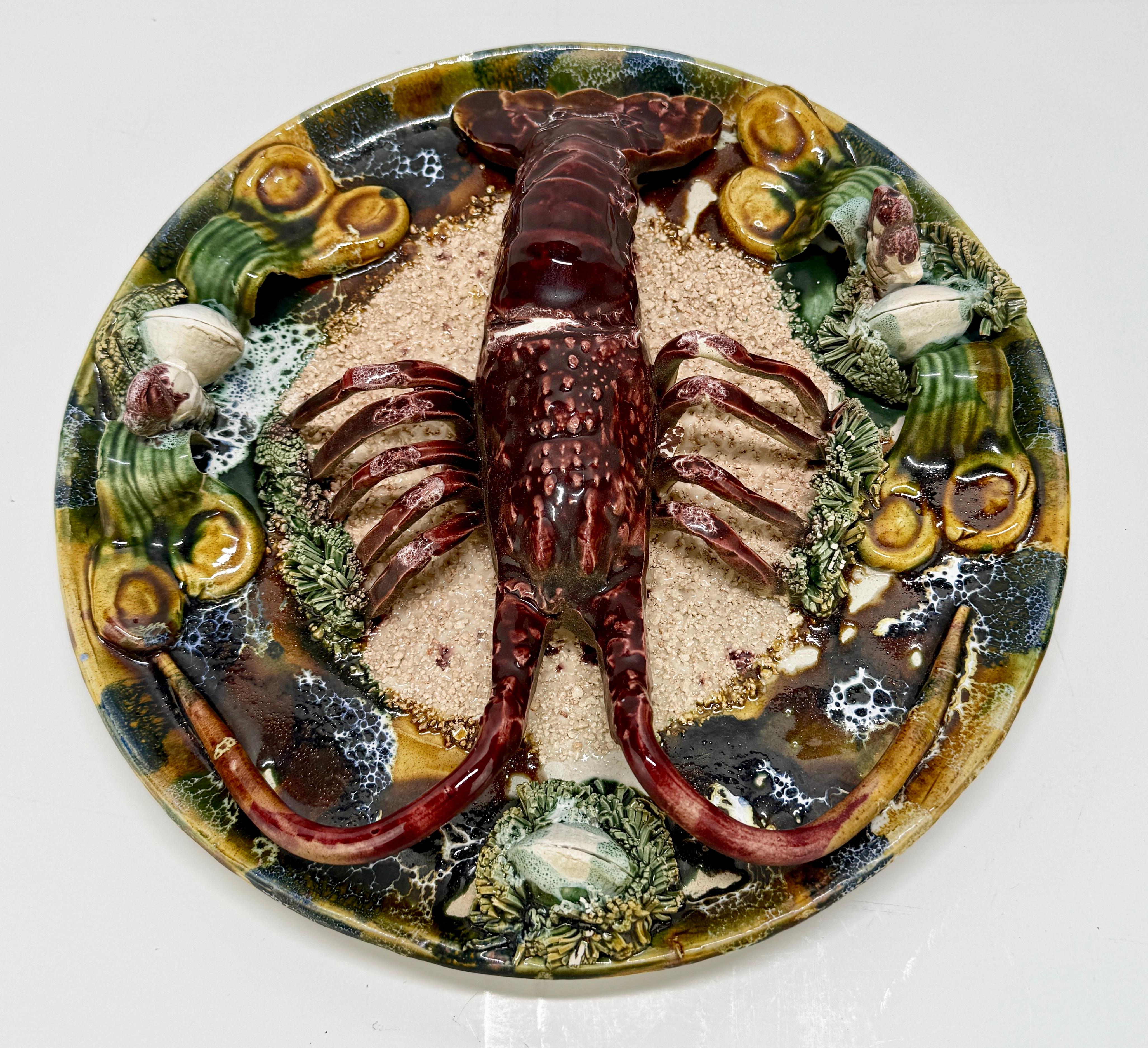 Il s'agit d'une plaque murale en majolique portugaise du milieu du XXe siècle, en haut-relief, représentant un homard sur une plage ou dans un marigot, attribuée à la tradition céramique de Caldas da Rainha. Le crustacé sculptural est modelé dans