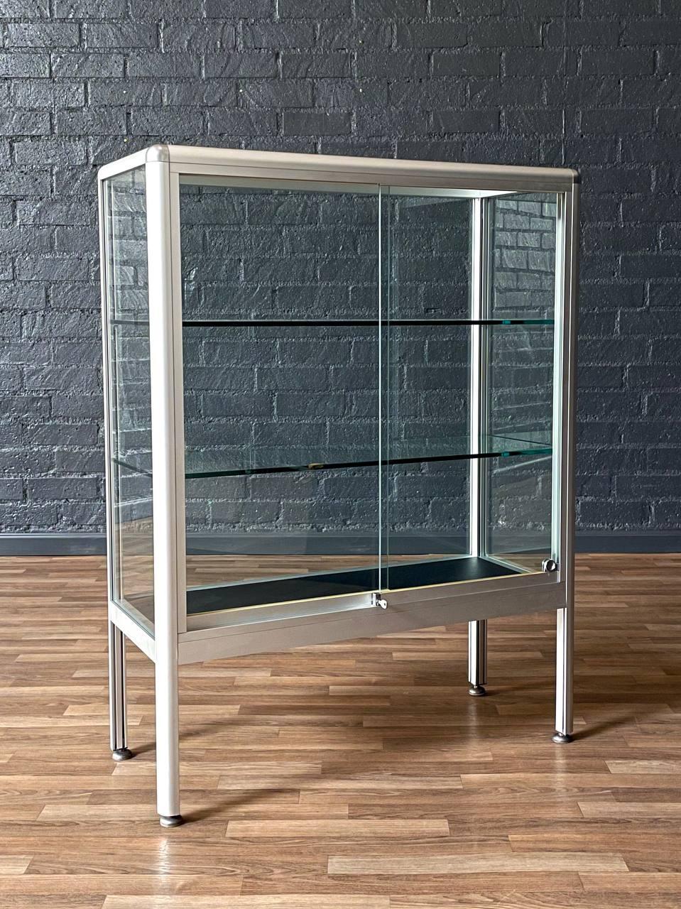 Condition: Original Vintage Condition
Materials: Aluminum, Glass, Has Key

This vintage Post Modern aluminum and glass bookcase shelf unit, c.1980’s, offers a sleek and functional design perfect for display or storage. Crafted with clean aluminum