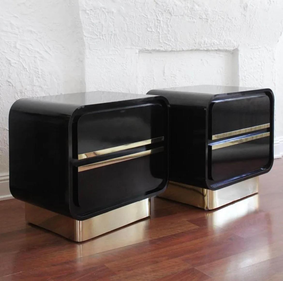 Vintage Post Modern two drawer black gloss lacquer nightstands, circa 1980. 

These sculptural style bedside tables feature a black gloss laminate and reflective gold brass trim. In the style of Karl Springer and Milo Baughman.

We're currently
