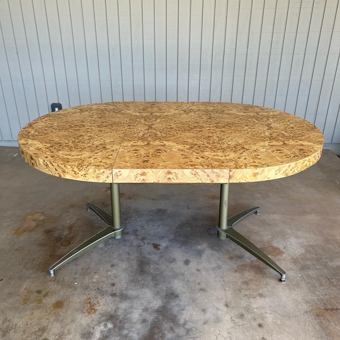 Burl wood veneer dining table with metal legs. In the style of Milo Baughman. Maker and designer unknown. Likely 1970s. It could be used as mid century modern, post modern, contemporary or Hollywood regency decor. The table is round or extendable to
