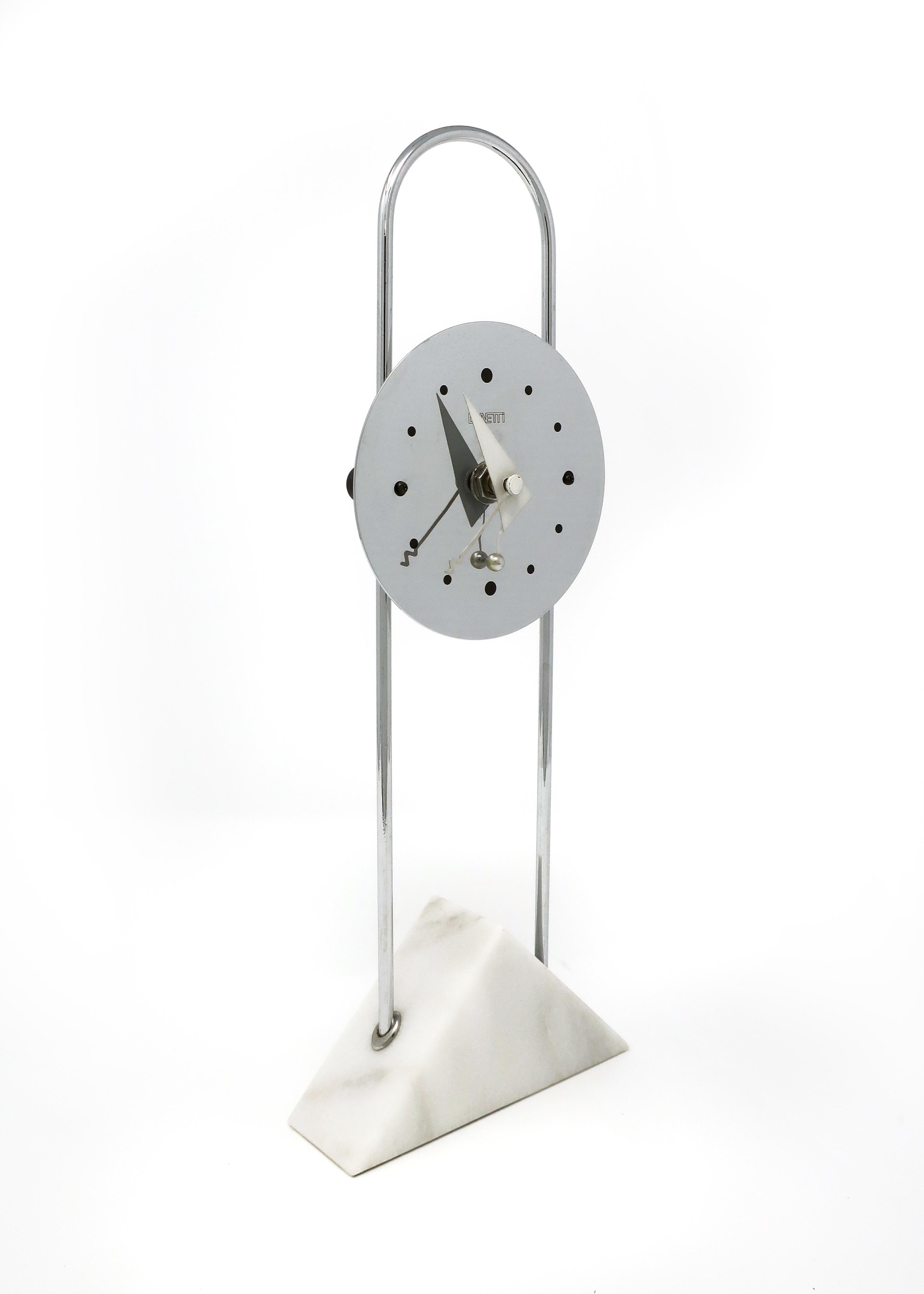 A stunning Postmodern clock by Canetti with a chrome face on an arching chrome stem set in a white marble base. Dated 1989, this clock screams its Memphis inspiration from the use of primary shapes to the quickly shapes of the clock’s hands. In