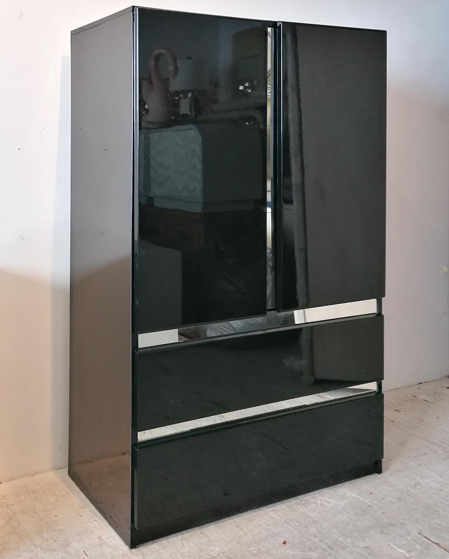 1980s deco revival black lacquer tall cabinet, by Millennium, USA. Looks like chrome edging, but is actually mirror glass. Double doors open onto shelved storage; 2 large drawers below. In great vintage condition.

We also have the matching