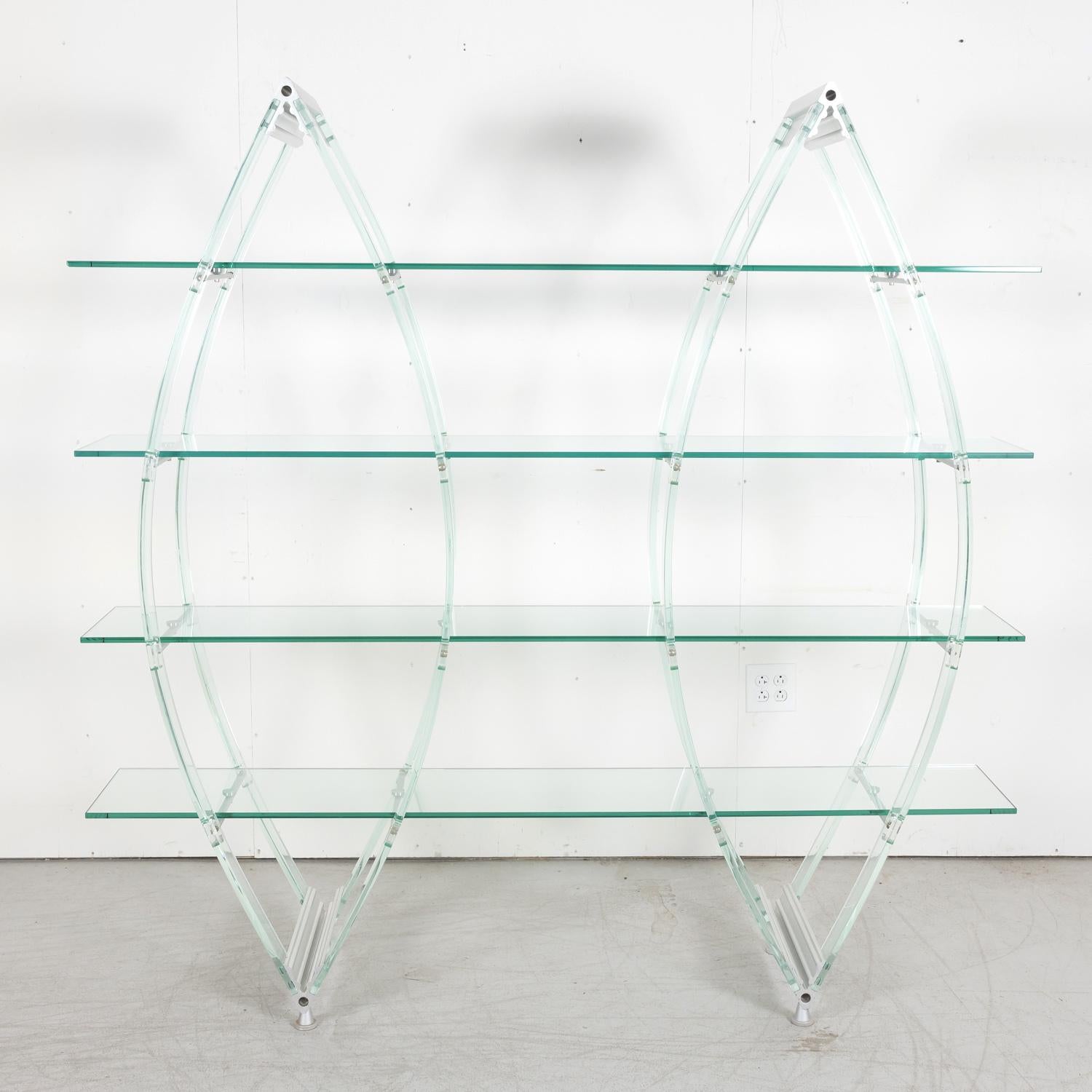 A vintage Italian Post-Modern bookcase or glass display unit having a refined sculptural form in the shape of double canoes featuring a minimalist acrylic and aluminum structure supporting 4 shelves made of tempered glass, circa 1980s. A versatile