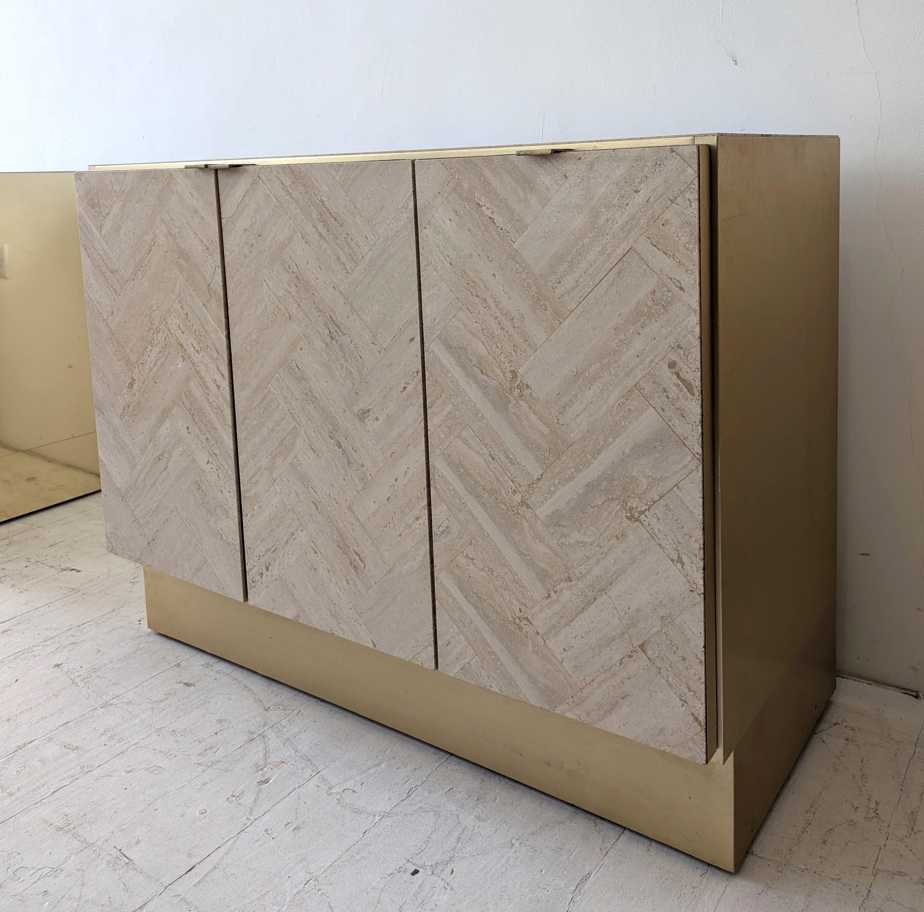 Meuble en travertin poli de Ello Furniture, années 1980. Cette armoire à 3 portes est dotée de poignées en laiton, de côtés en métal doré brossé et d'un socle en métal doré brossé.
Le métal présente une petite patine liée à l'âge.

Nous avons