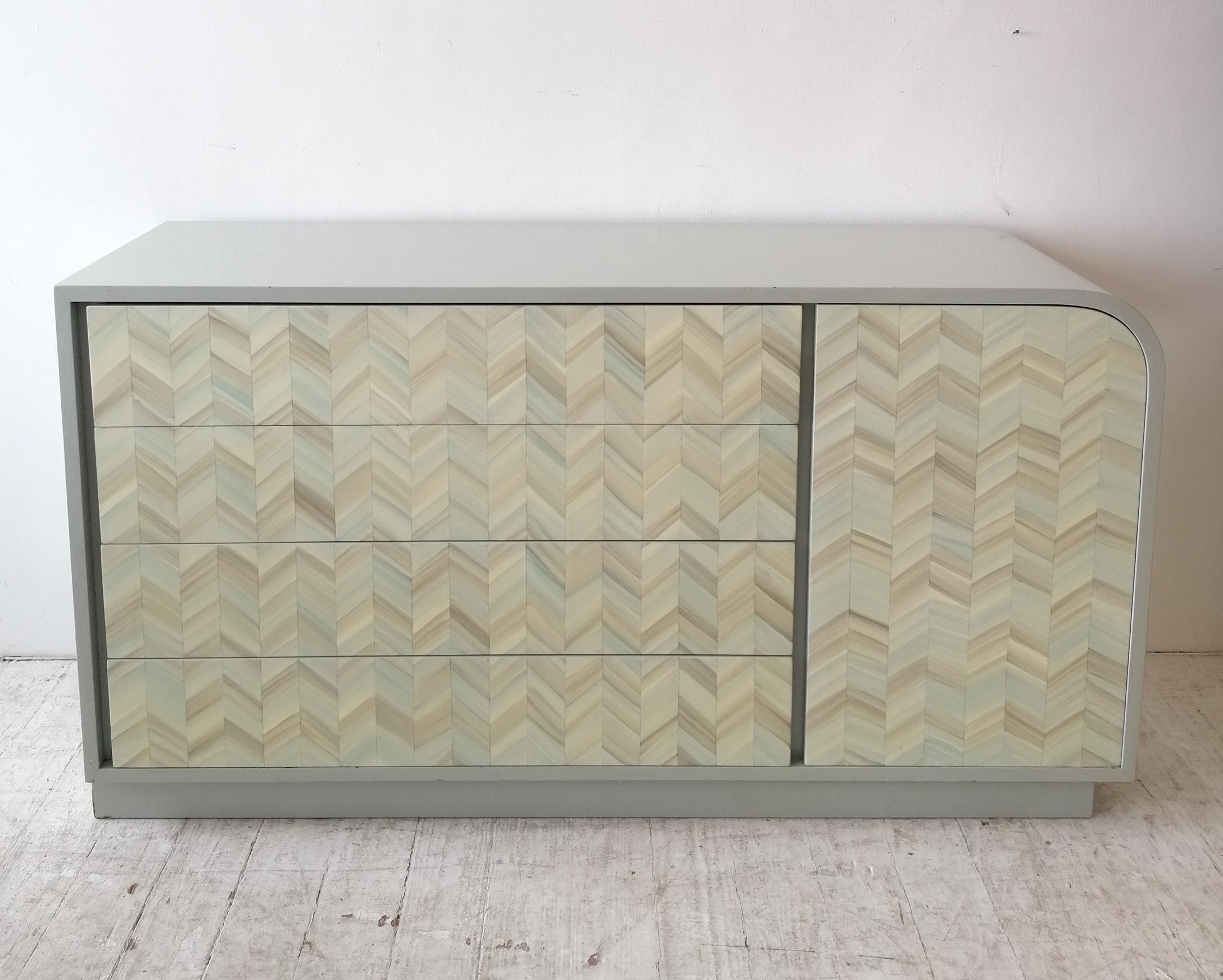 An unusual postmodern American lacquered waterfall sideboard with trompe l'oeil chevron design on front.
The rest of the body is glossy grey which has some touched-up areas of wear, mostly on the waterfall end. The left hand end is meant to be