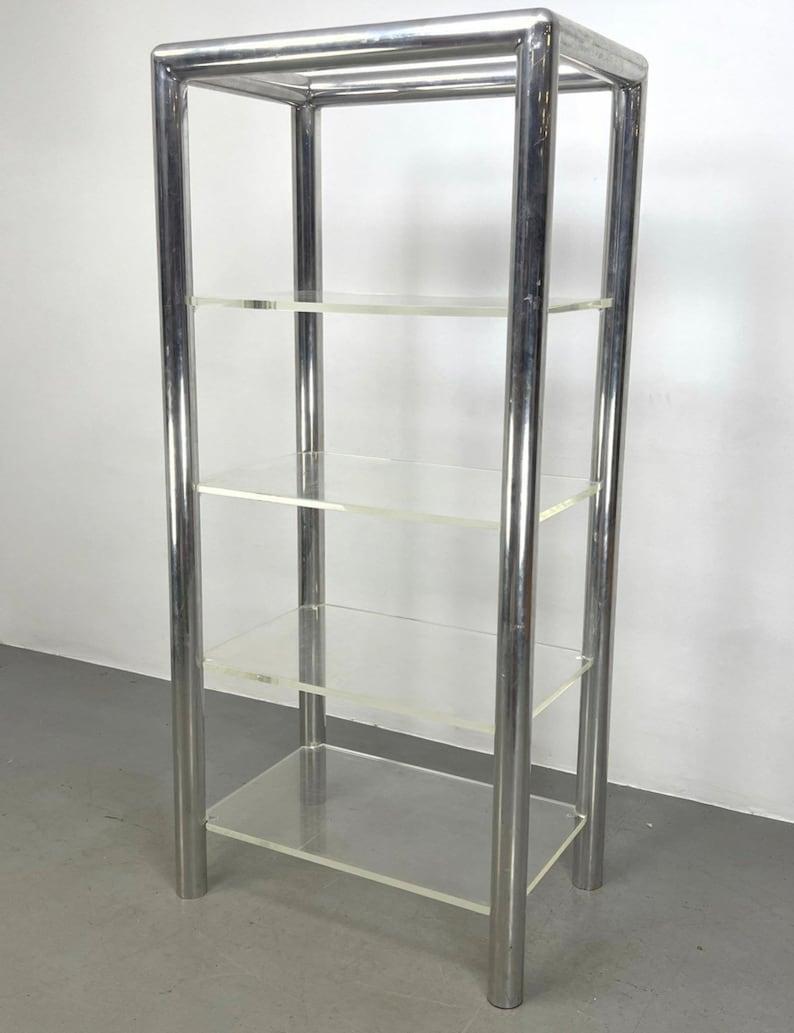 Vintage Postmodern Chrome & Lucite Shelf—a fusion of timeless elegance and modern design. Its sturdy chrome frame seamlessly complements the translucent allure of lucite shelves, creating a visually striking piece. Ideal for showcasing collectibles