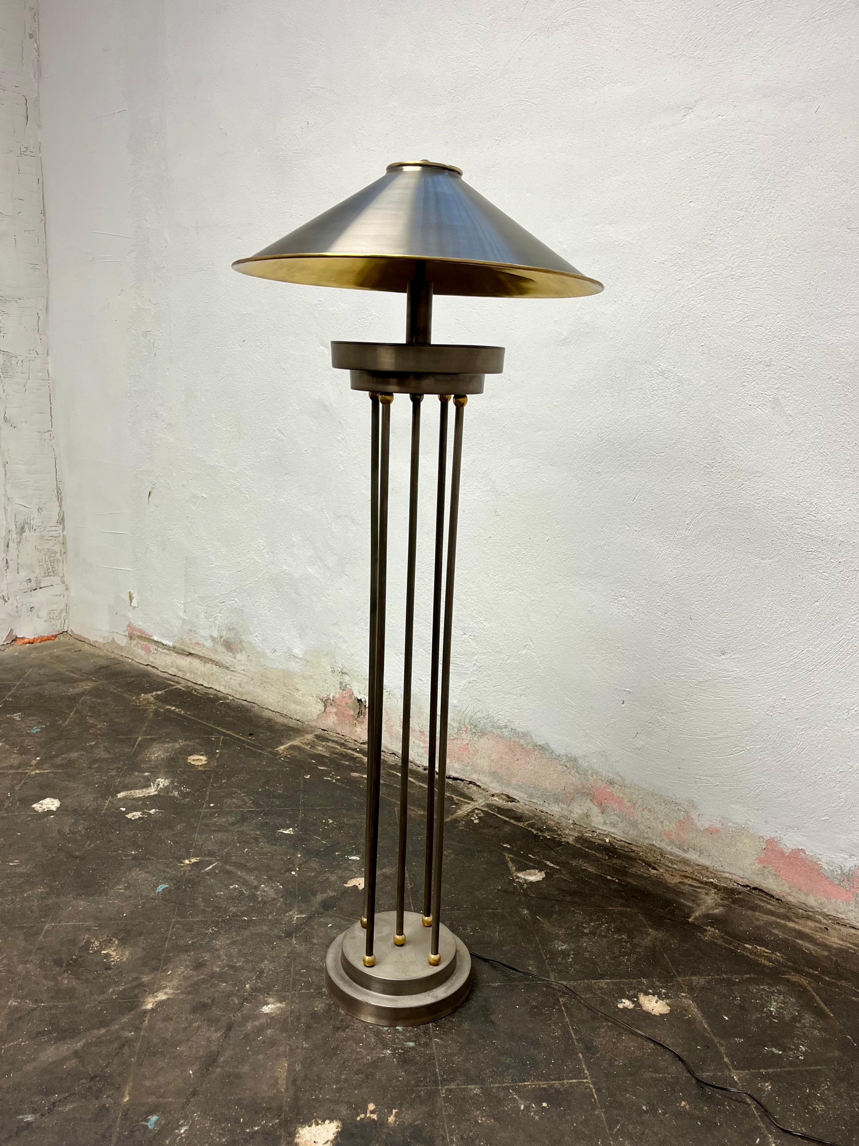 Striking post modern steel and brass columnar floor lamp. Dramatic presence with a metal shade topped with a heavy brass finial and brass interior to cast soft yet adequate lighting. 5 slender rods capped with brass balls sit atop a stepped circular