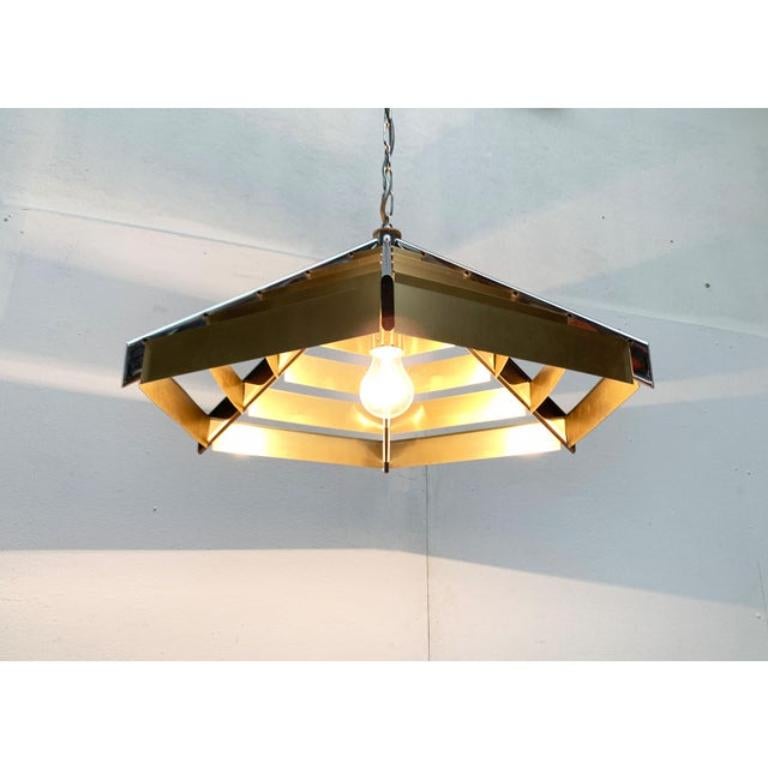 Lampada a sospensione postmoderna con struttura elaborata.

un design postmoderno che convince per la sua geometria chiara e la sua materialità. La lampada ha la forma di una piramide piatta ed esagonale. Sei ponti si uniscono in un punto centrale e