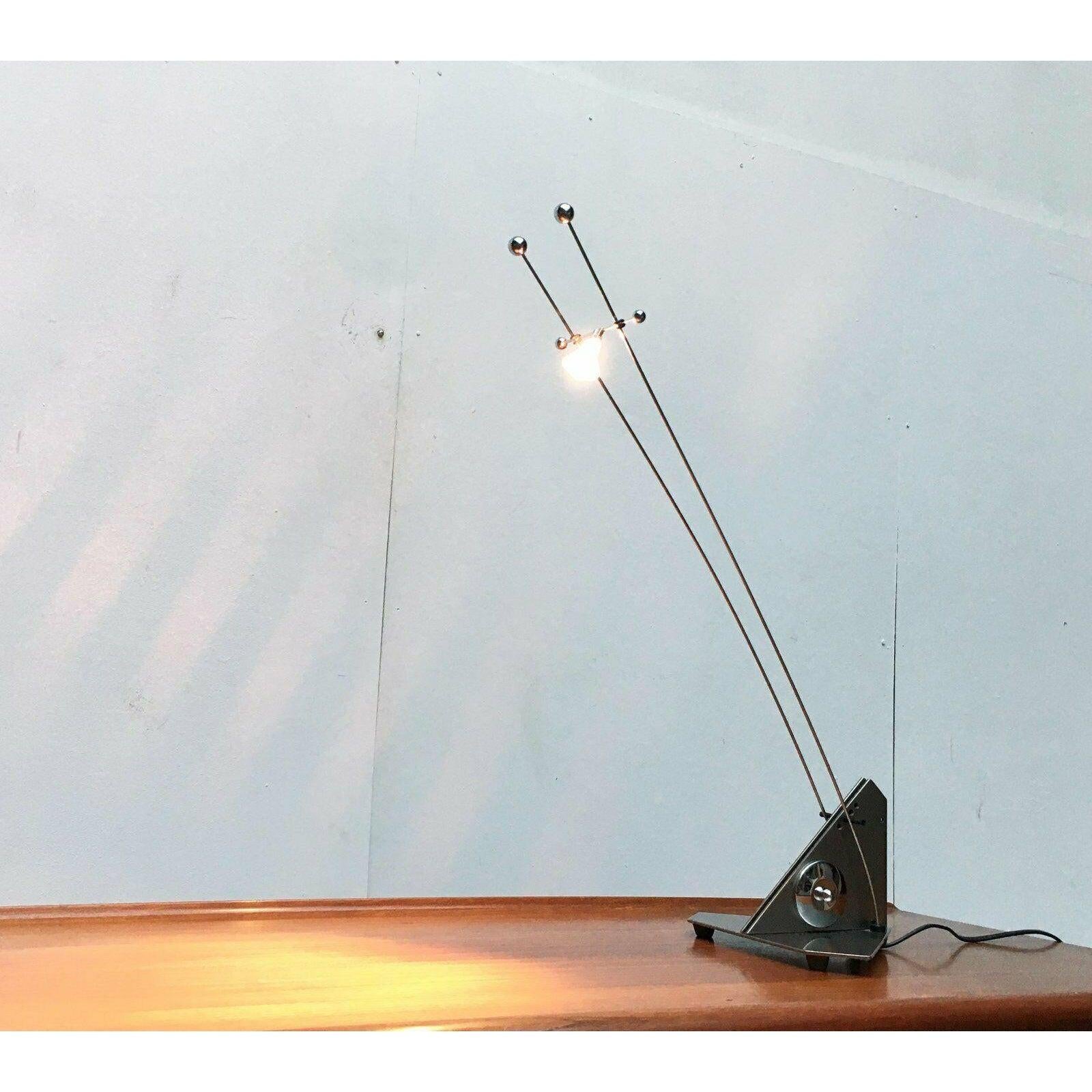 Lámpara de mesa halógena de bajo voltaje Filigrana.

Un diseño muy técnico. Reducido a lo esencial. La inclinación de las dos varillas puede ajustarse manualmente mediante un orificio en la base y una pequeña varilla de plástico. La cabeza de la